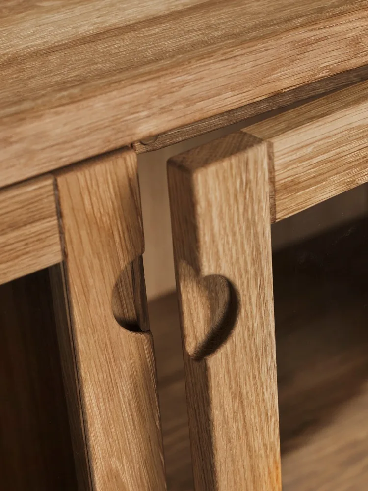 Zwei helle Holzplatten, jeweils mit einem herzförmigen Ausschnitt, an einem Möbelstück.