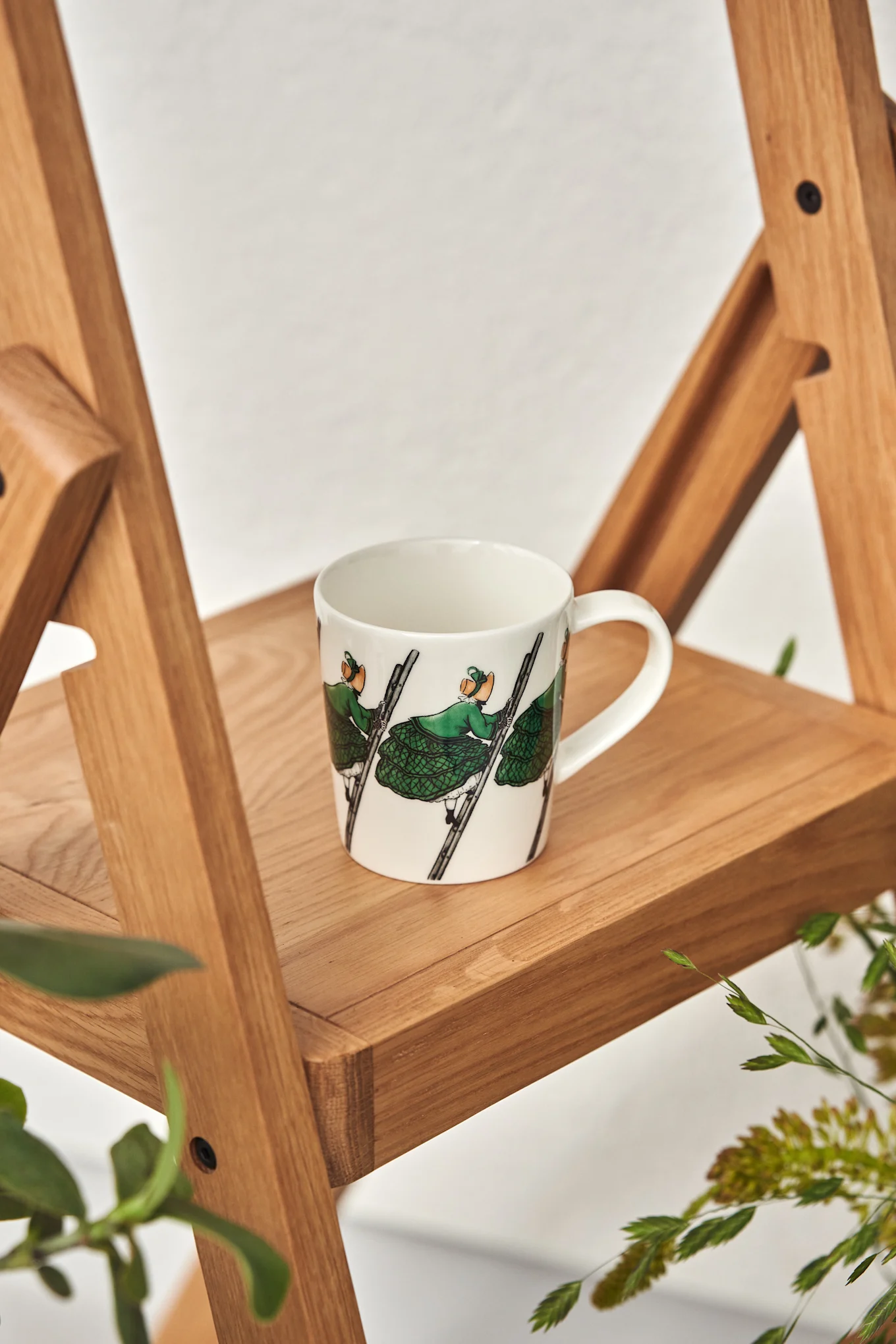 Eine Tasse mit dem Tant Grön-Motiv der schwedischen Kinderbuchautorin Elsa Beskow auf einer Leiter von Design House Stockholm.