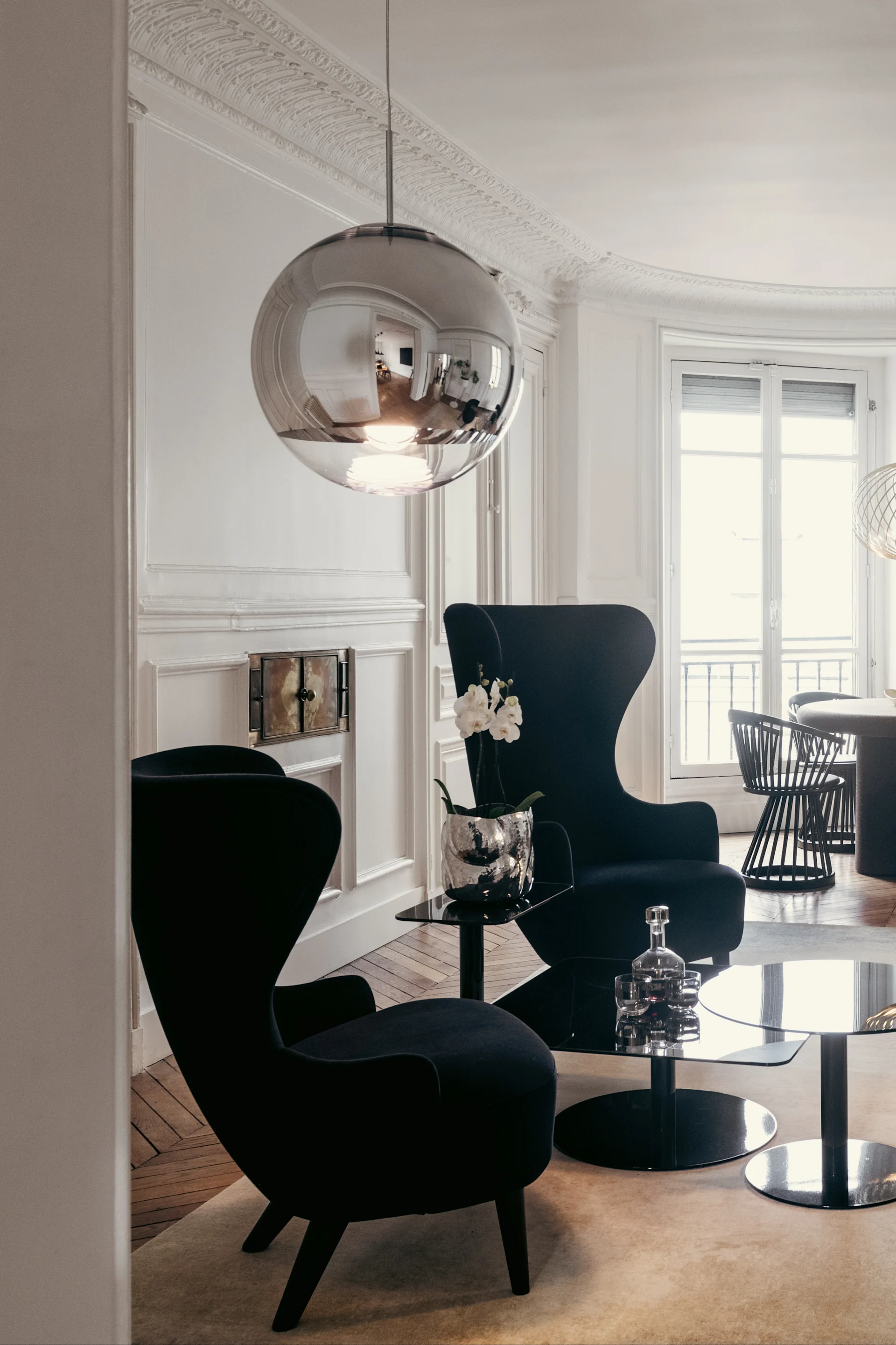 Deckenleuchte Wohnzimmer: Die chromfarbene Pendelleuchte Mirror Ball von Tom Dixon hängt in einem modernen Wohnzimmer.