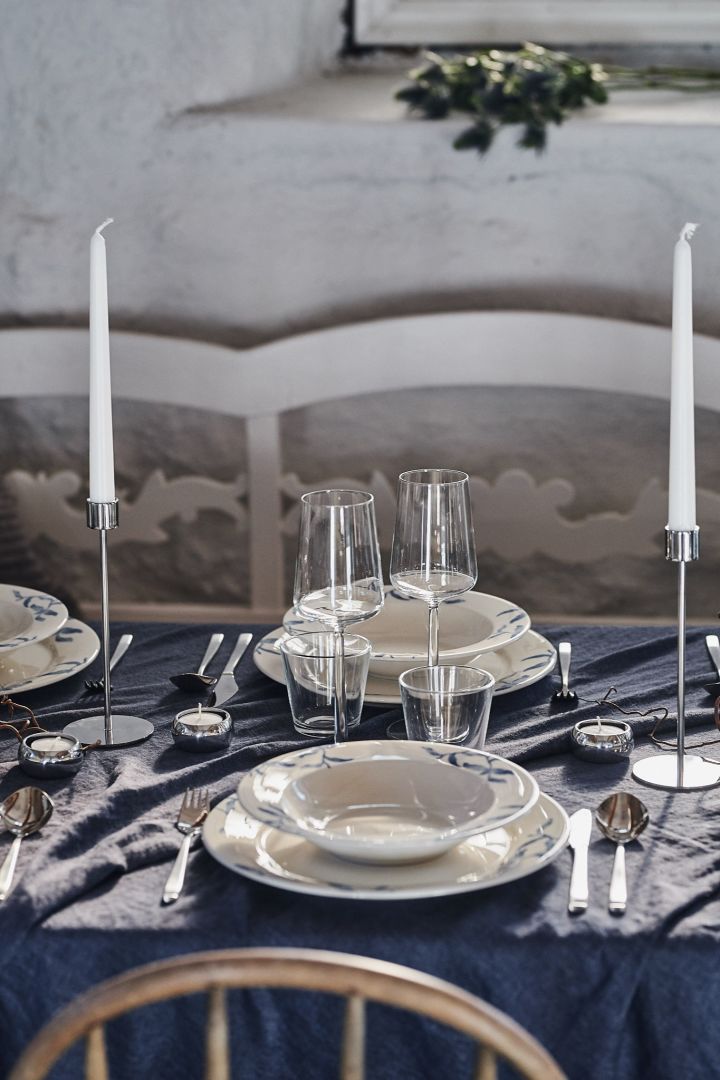 Ein gedeckter Tisch mit blau-weißem Porzellan und Essence Weingläsern von Iittala in einem rustikalen Ambiente. 