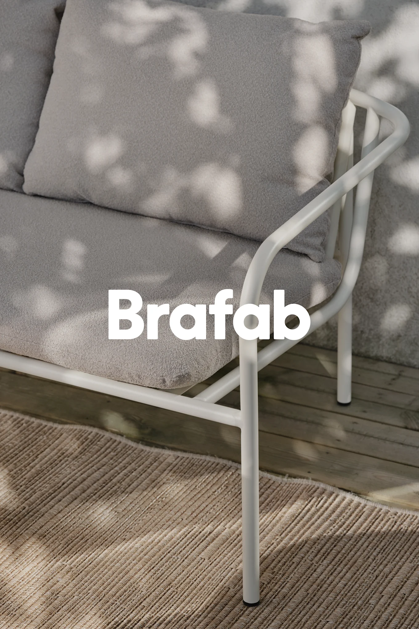 Brafab-Logo über einem hellgrauen Outdoor-Sofa mit weißem Metallrahmen, auf einem beigen Teppich auf Holzterrasse mit Schatten.