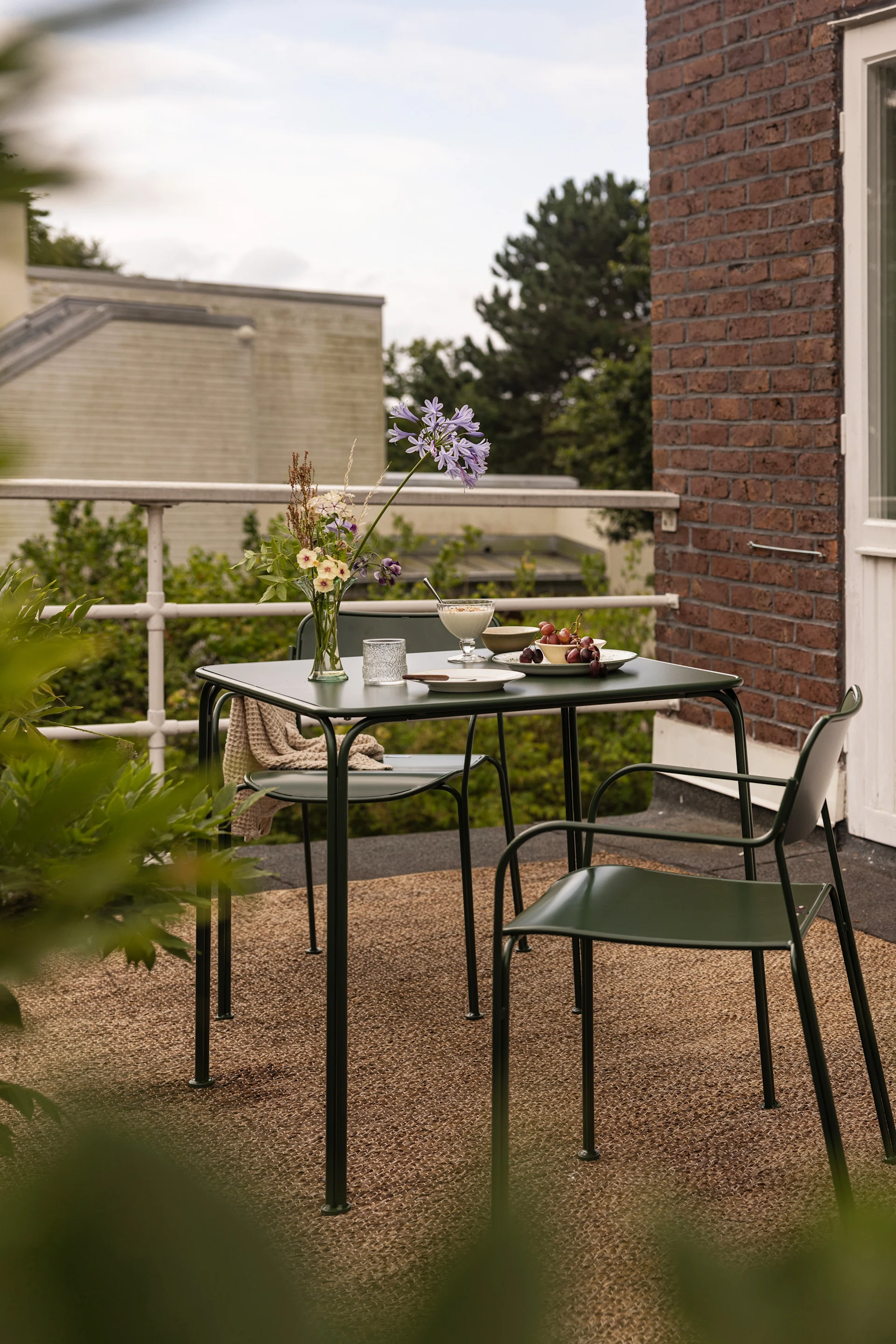 Ein Tisch und zwei Stühle aus der Libelle-Kollektion von Grythyttan stehen auf einem Balkon.