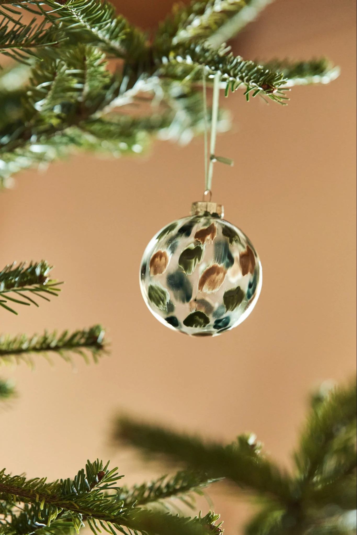 Dekorieren Sie Ihren Baum dieses Jahr mit dem Weihnachtsbaumschmuck 2021 in den 4 verschiedenen Stilen der Nest Trends – Nurture, Share, Boost und Cultivate.  Hier sehen Sie die Sternenspitze von Broste Copenhagen in einer gold-braunen Farbe neben einer zarten Lichterkette. 