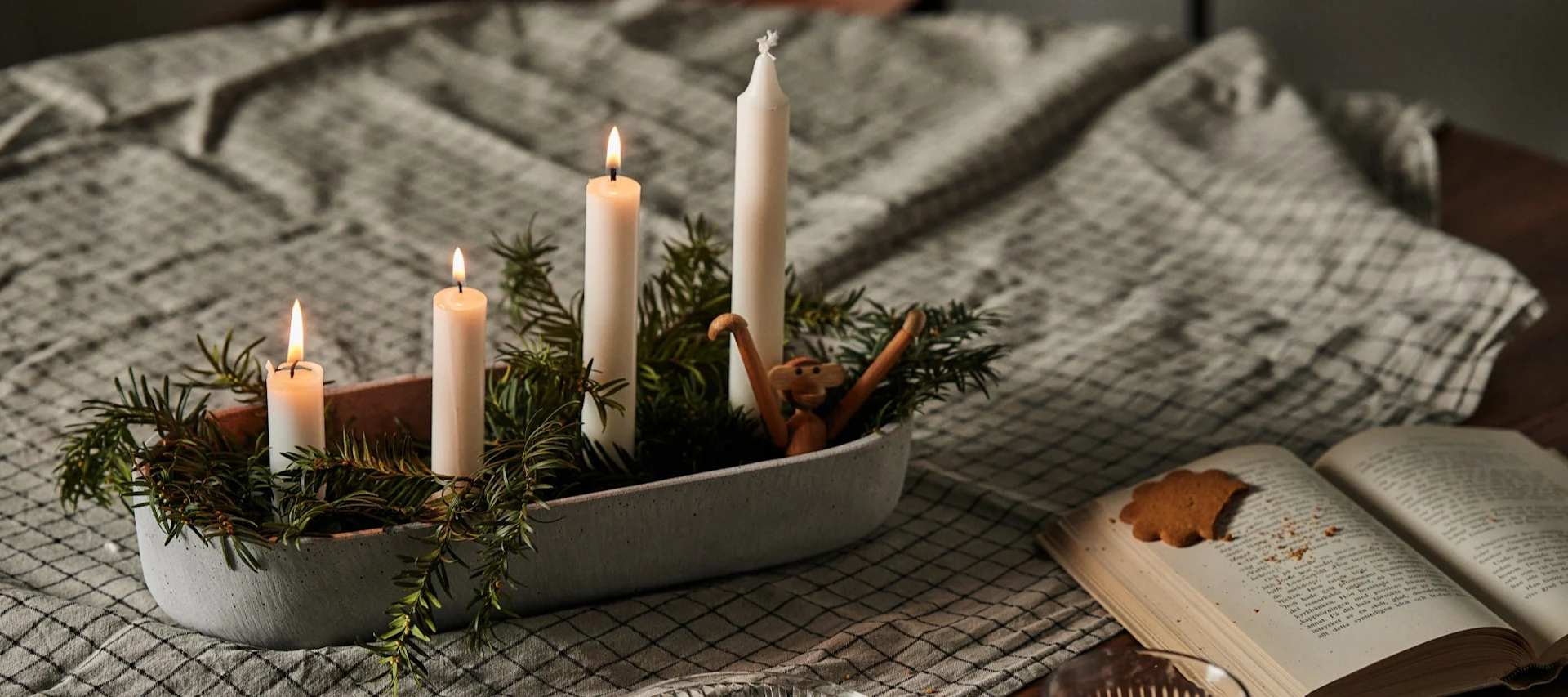 Der Adventskranz-Kerzenhalter Marb von House Doctor ist mit Kerzen und Tannengrün dekoriert und steht auf einem Tisch.