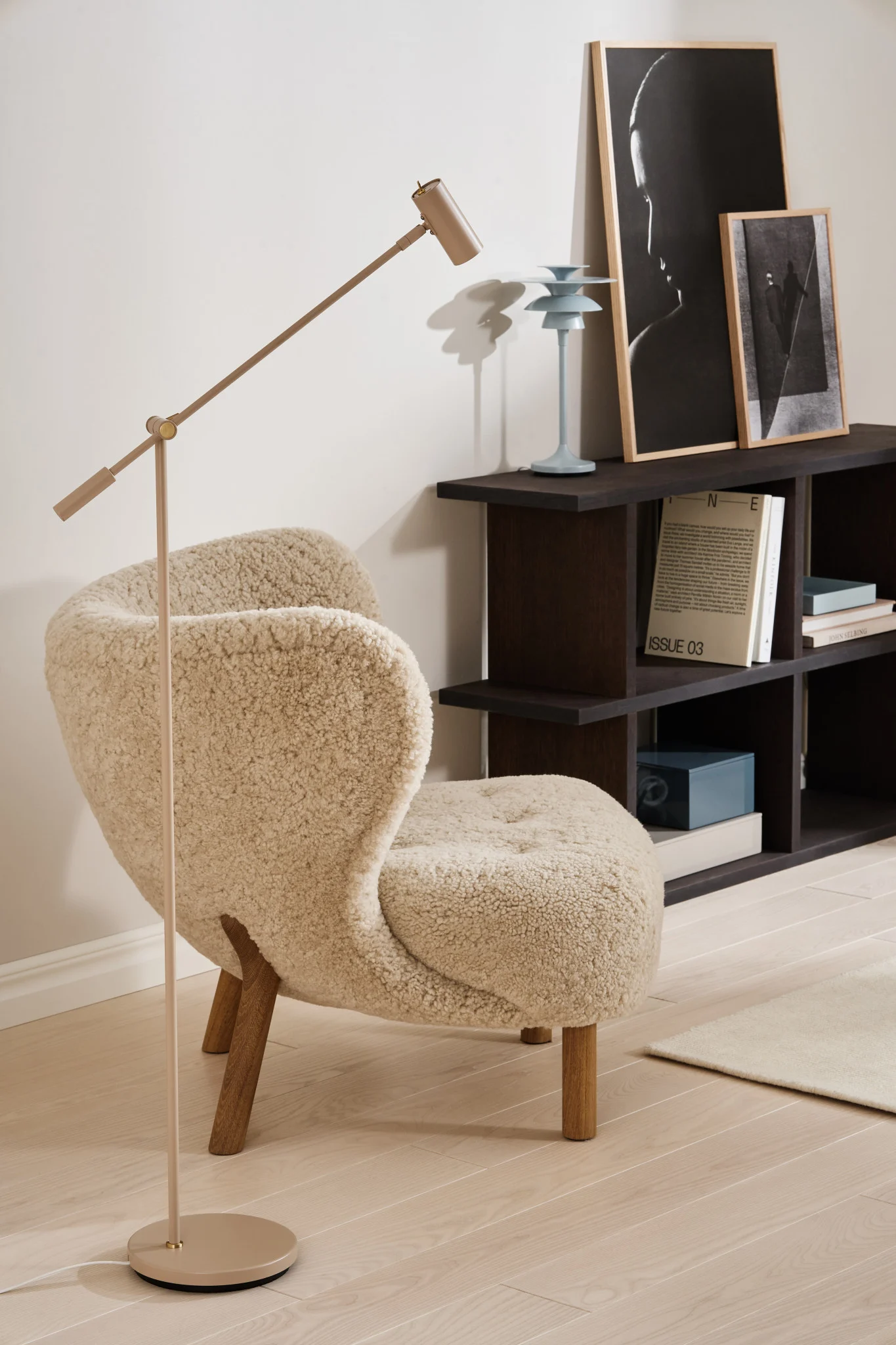 Lichtgestaltung: Die nougatfarbene Cato Stehleuchte von Belid steht in einem beige-schwarzen Wohnzimmer, davor der Little Petra Sessel von &Tradition.