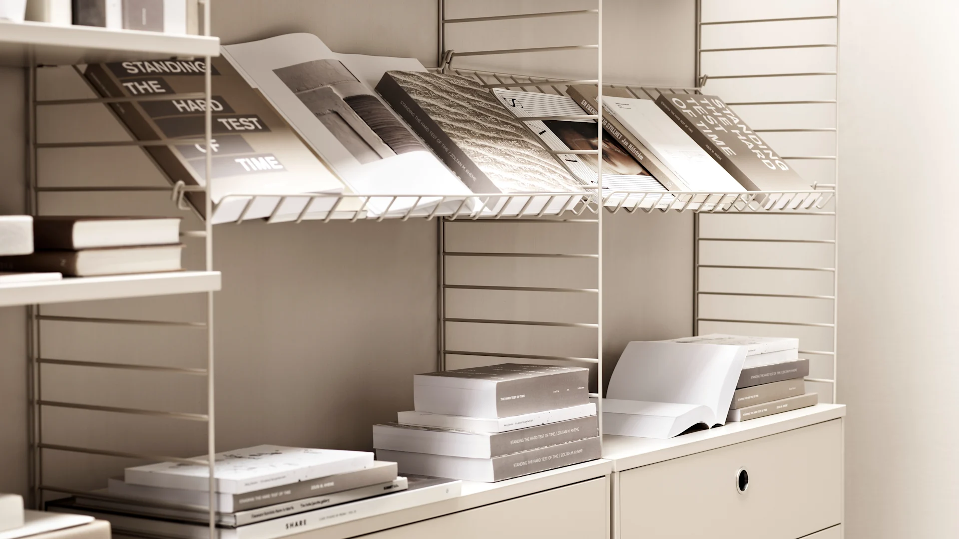 String Regalsystem: Hier sehen Sie ein String Regal in Weiß und Beige, welches zur Präsentation und Verwahrung von Büchern verwendet wird.