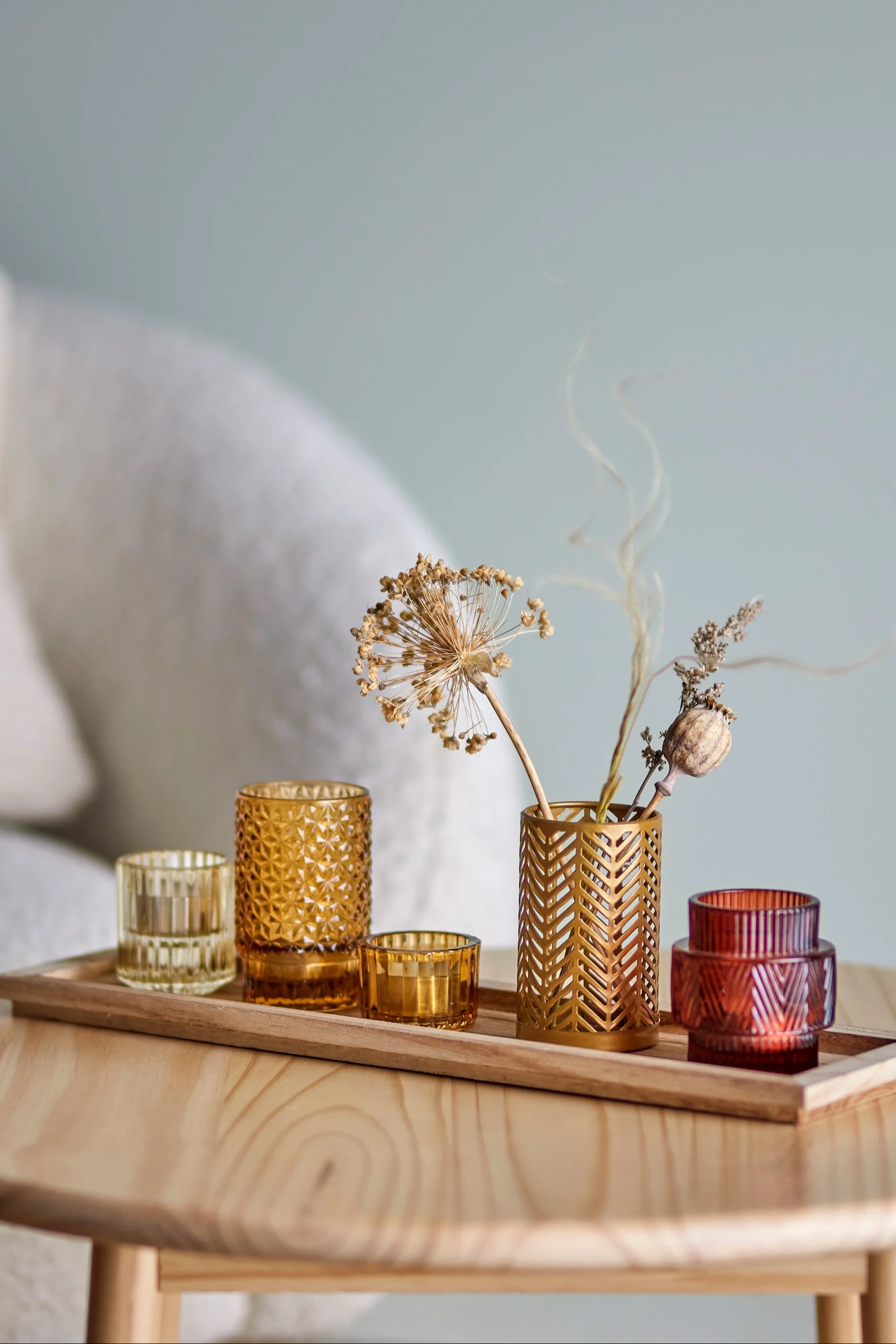 Die perfekte Boho Deko: Das Sanga Tablett mit Windlichtern in Gelb- und Rottönen von Bloomingville auf einem Wohnzimmertisch.