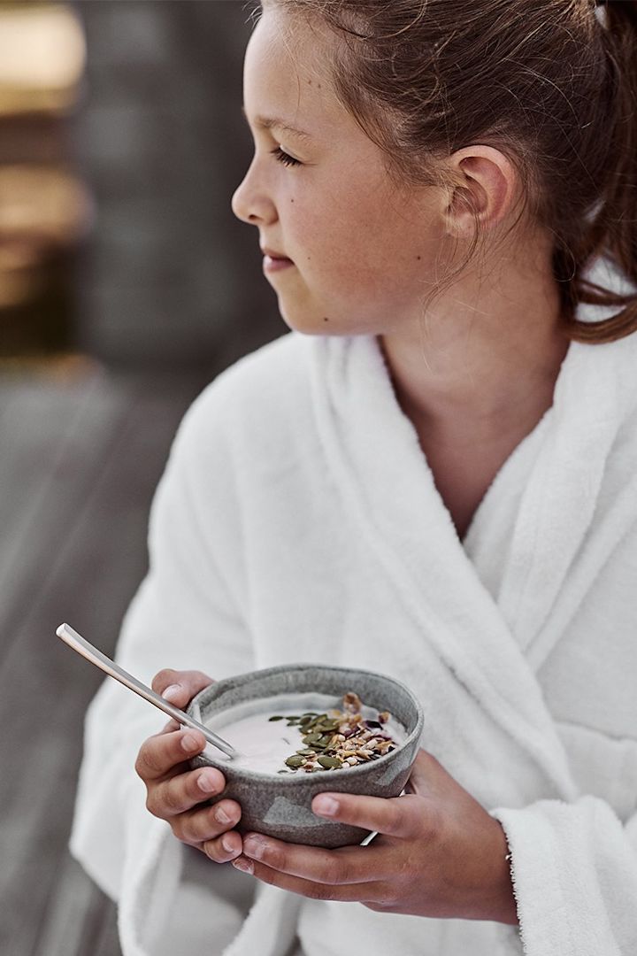 Eine einfache Smoothie-Bowl mit Joghurt und Kürbiskernen, serviert aus einer kleinen grauen Schale von Mateus, belebt den Morgen. 