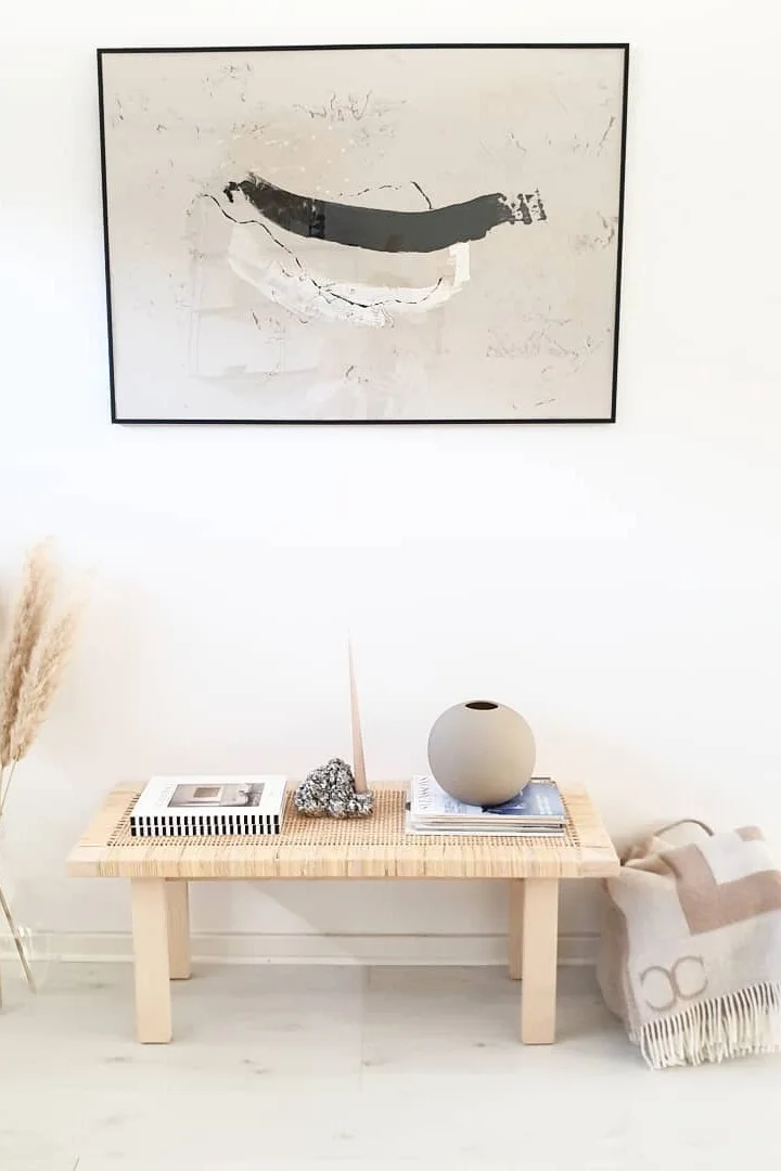 Japandi: Hier sehen Sie eine Bank dekoriert mit der Ball-Vase von Cooee Design, daneben eine Decke von Classic Collection und einem Bild darüber.