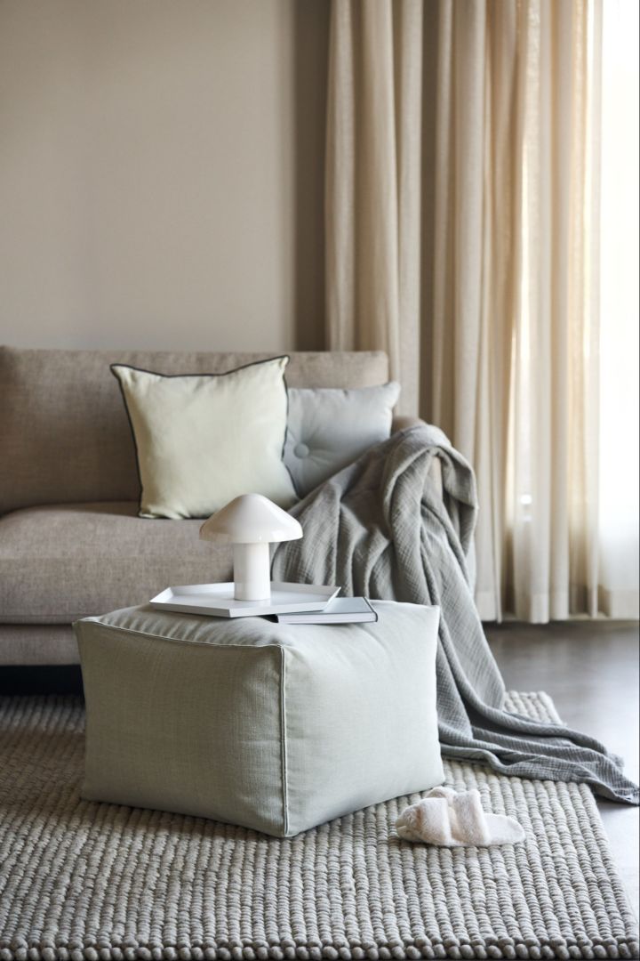 Die Decke Crinkle in Grau und die tragbare Lampe Pao von HAY in einem neutralen Wohnzimmer. 