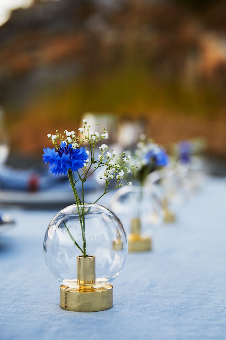 Krebsfest in Schweden: Die Orbis Vase von Klong steht auf einem gedeckten Tisch im Freien, dekoriert mit blau-weißen Blumen.
