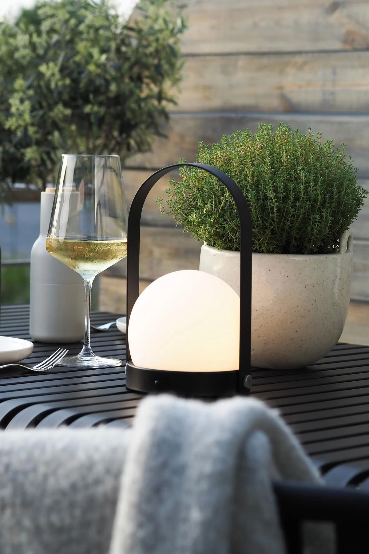 Die tragbare Carrie-Leuchte von Audo Copenhagen und der Speckle Blumentopf von Ferm Living stehen auf dem Palissade-Tisch von HAY auf der Terrasse von @wohngluecksieben.