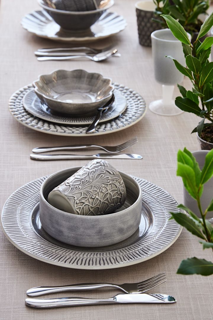 Ein mit grauem Geschirr aus den Stripes, MSY- und Lace-Kollektionen von Mateus gedeckter Tisch.