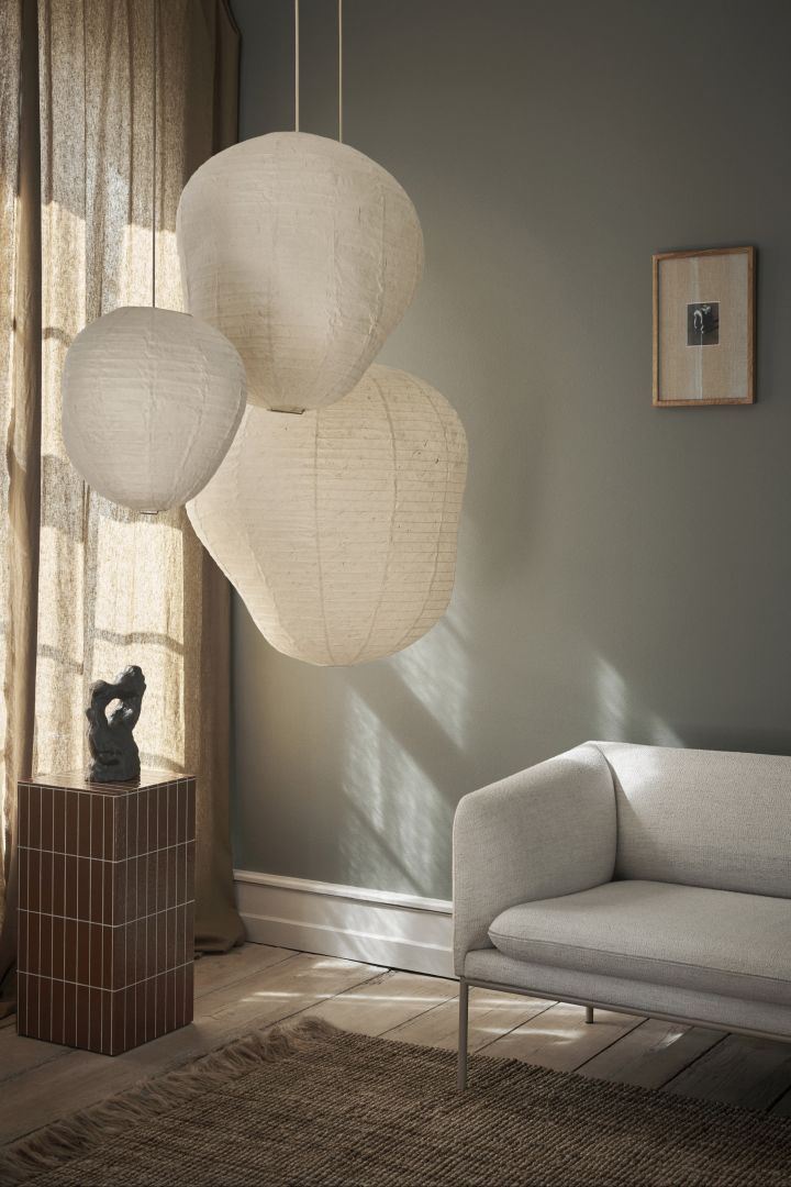 Die richtige Deckenleuchte fürs Wohnzimmer finden: Hier sehen Sie die Kurbis Lampenschirme von Ferm Living in verschiedenen Größen in einem hell eingerichteten Wohnzimmer hängen.