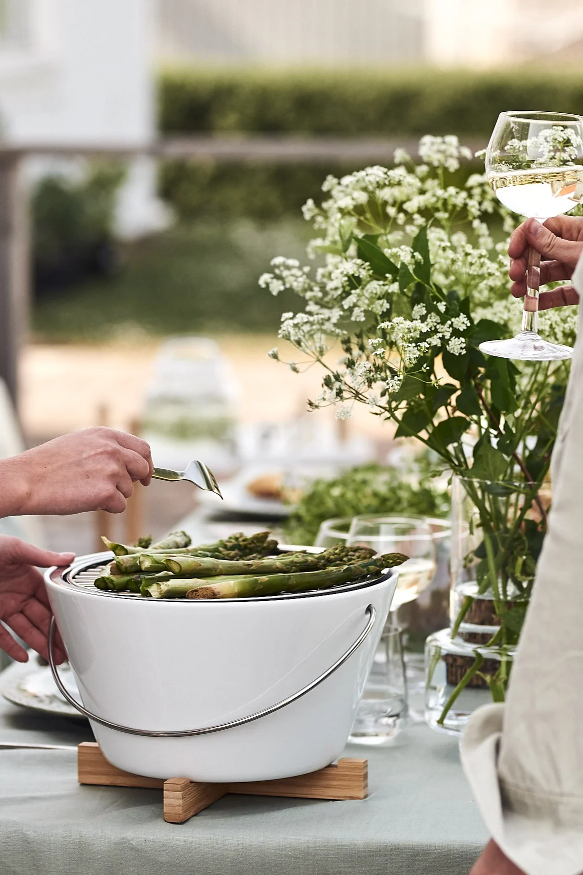 Der Eva Solo Tischgrill steht auf dem Tisch bei der Gartenparty, wo köstlicher Spargel gegrillt wird. 