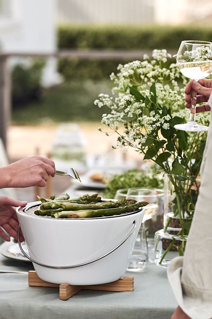 Der Eva Solo Tischgrill steht auf dem Tisch bei der Gartenparty, wo köstlicher Spargel gegrillt wird. 