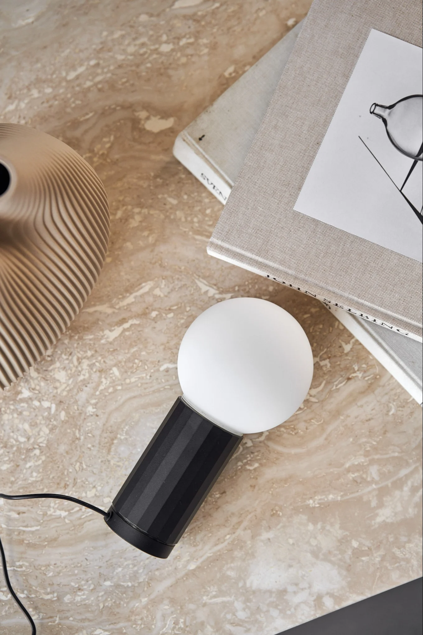 Die Turn On Tischleuchte von HAY liegt auf einem Marmortisch. 