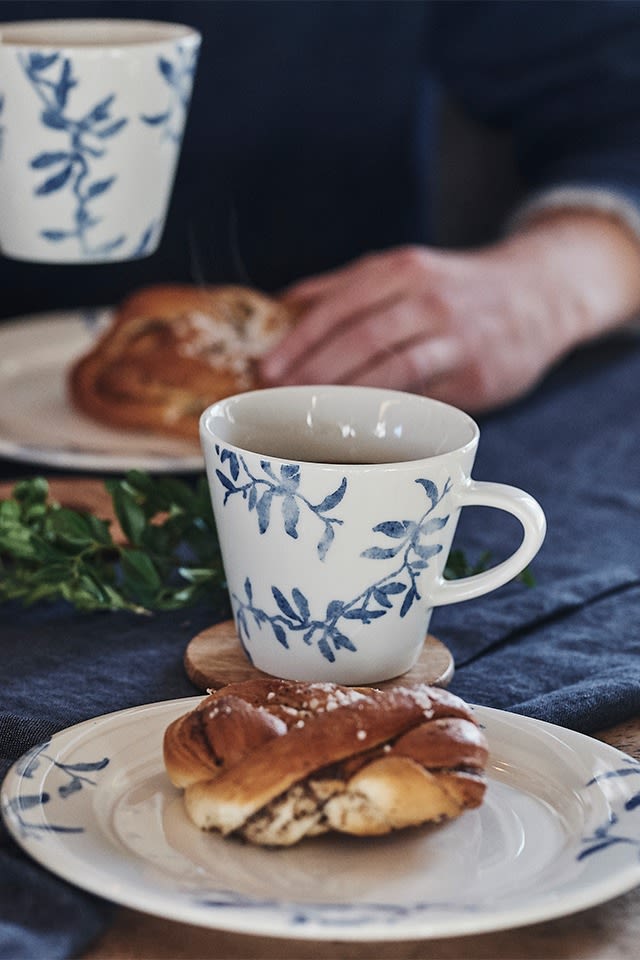 Typisch schwedische Fika mit Kaffee und Zimtschnecke, serviert auf blau-weißem Porzellan von Scandi Living. 
