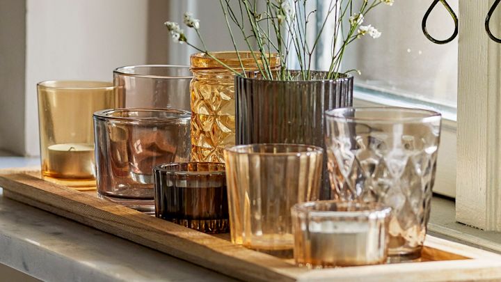 Die perfekte Boho Deko: Das Sanga Tablett mit Teelichthaltern in verschiedenen Gelb- und Brauntönen von Bloomingville steht auf einer Fensterbank.