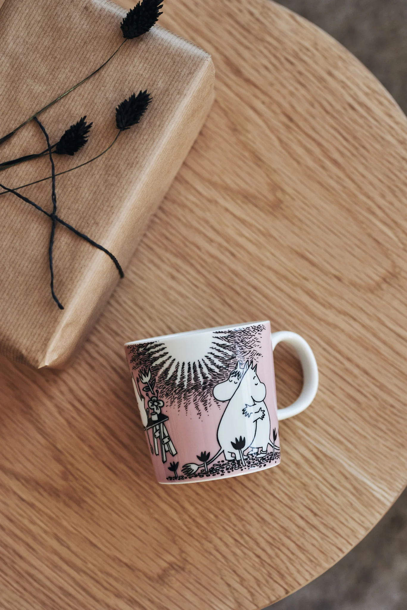 Auf einem Tisch liegt die rosafarbene Liebe-Tasse von Moomin Arabia - das tolles Geschenk zum Valentinstag.