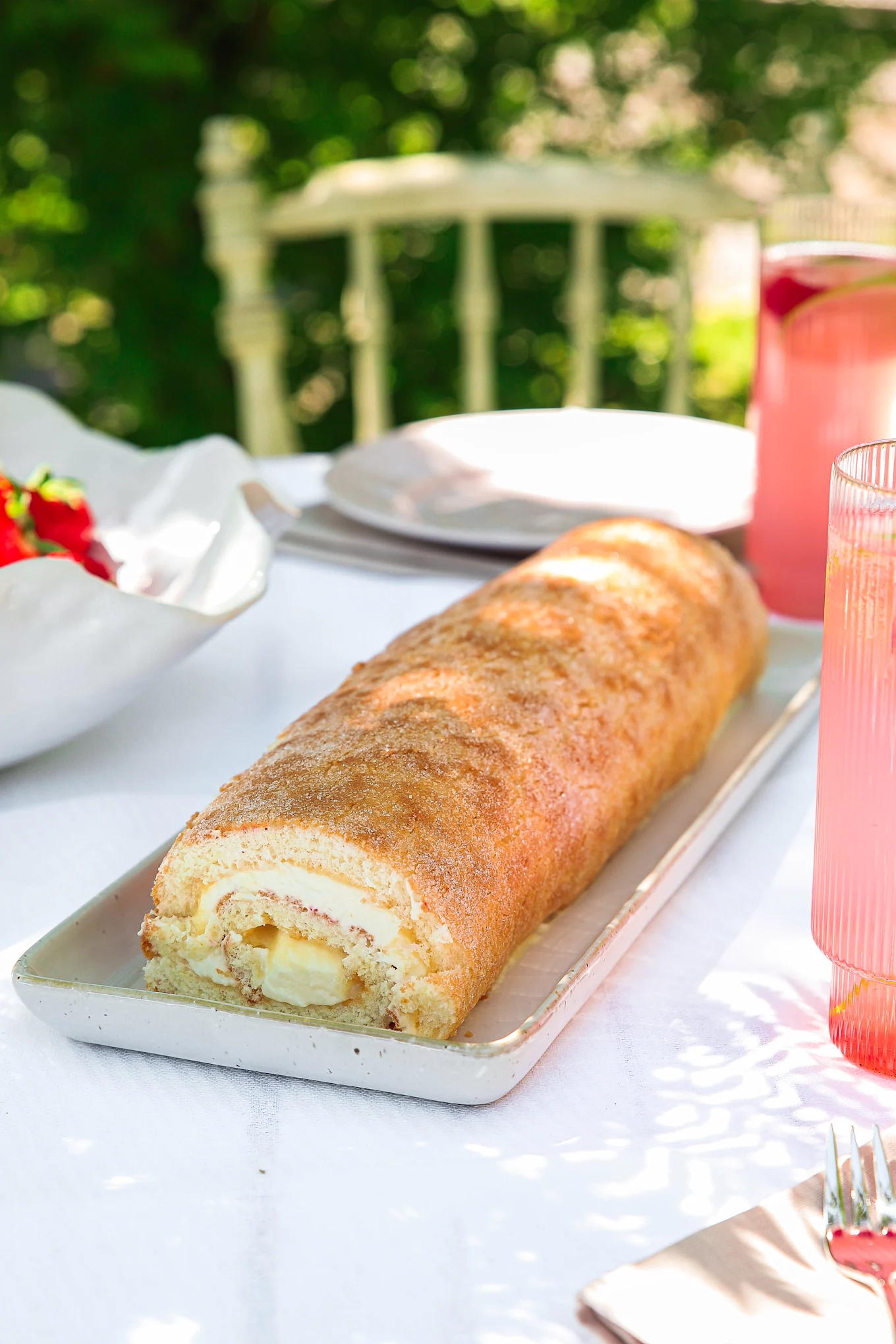 Eine perfekte Biskuitrolle steht auf einem sommerlich gedeckten Tisch.