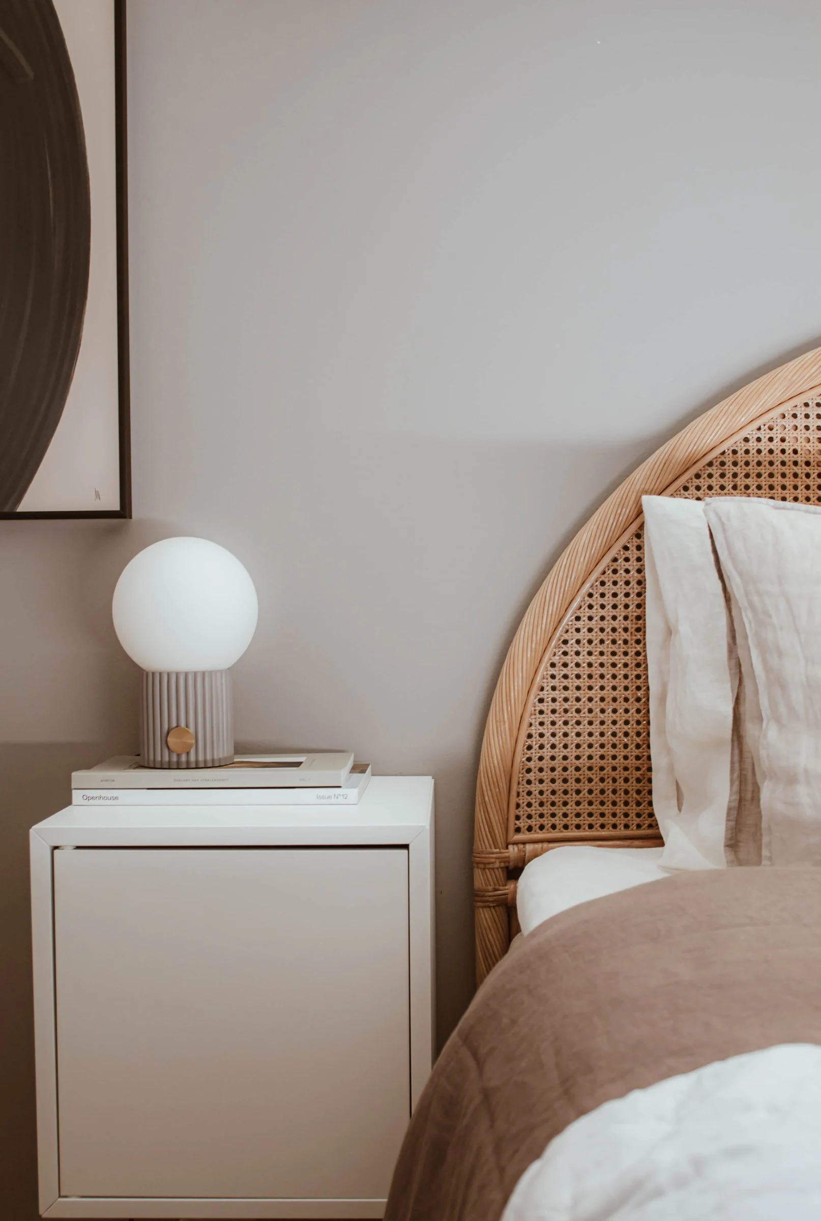 Die graue Hubble Tischleuchte steht auf dem Nachttisch eines im Boho-Stil eingerichteten Schlafzimmers.