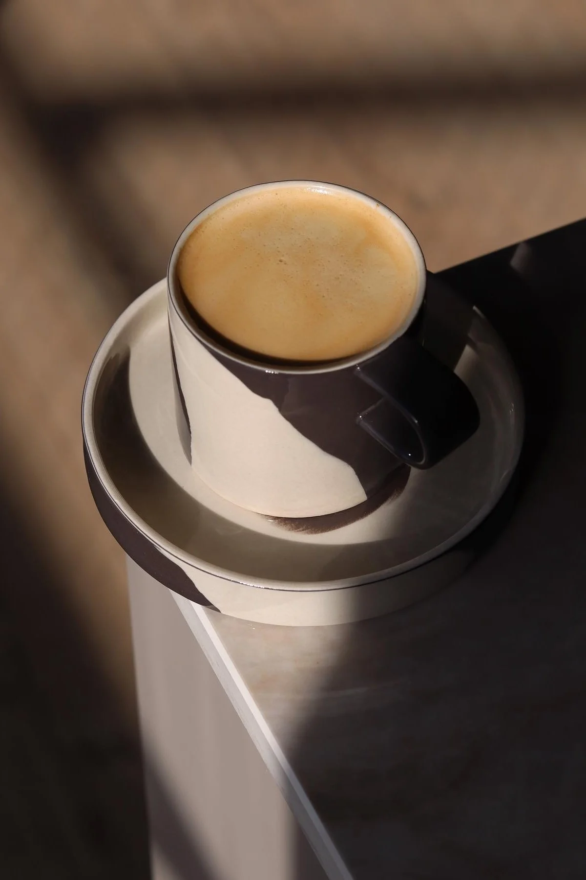 Die schwarz-weiß gemusterte Inlay Tasse von Ferm Living steht auf einer Tischecke im Zuhause von @saraelineeriksen.