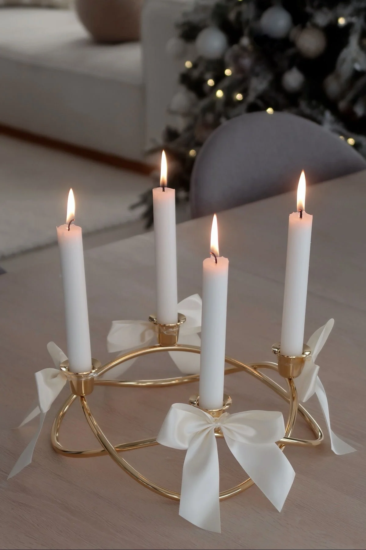 Der goldene, mit Schleifen dekorierte Season Kerzenhalter von Georg Jensen steht auf einem Tisch.