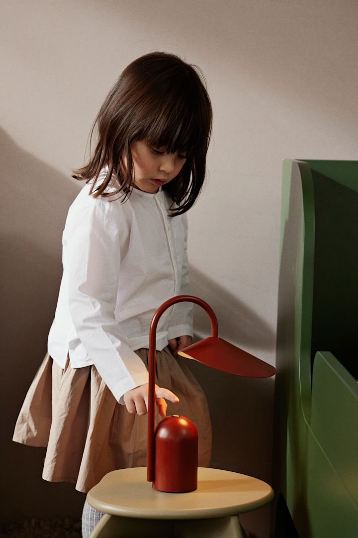 Ein Kind drückt den Schalter an der roten tragbaren Lampe Arum von ferm LIVING. Tragbare Beleuchtung ist eine tolle Idee für ein Kinderzimmer. 