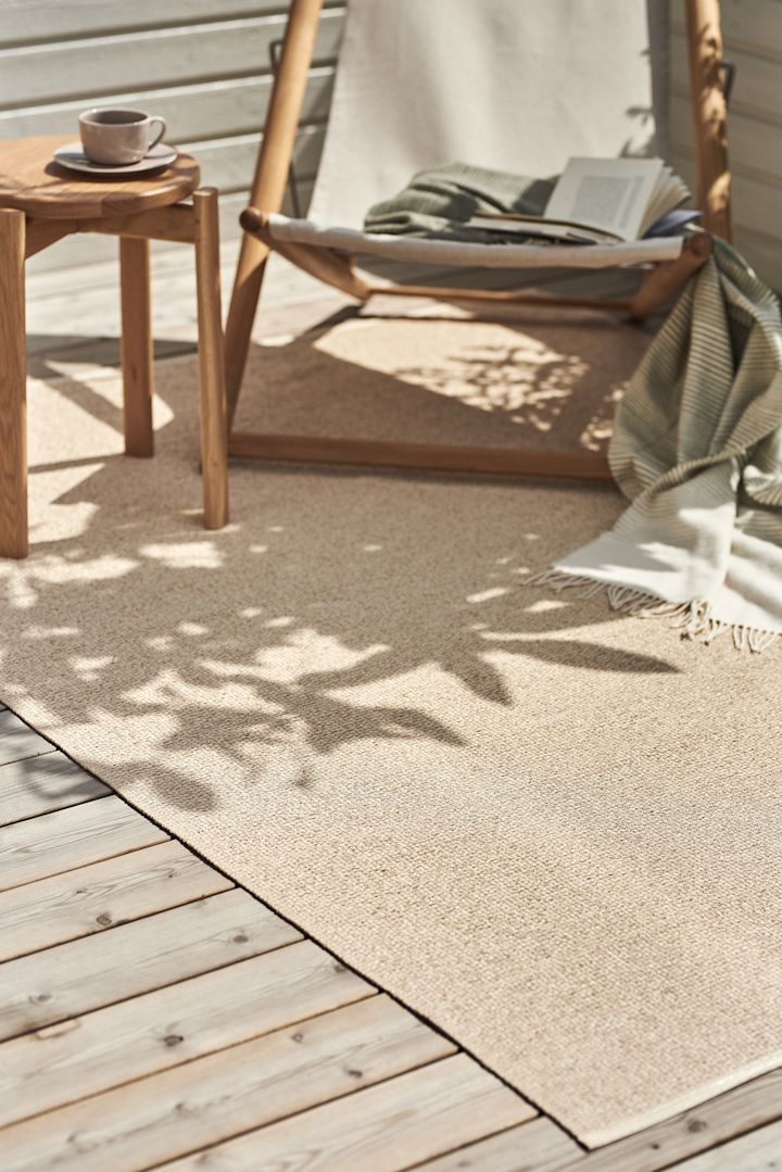 Der Mellow Kunststoffteppich von Scandi Living liegt auf einem Balkon, darauf stehen ein Liegestuhl und ein kleiner Tisch. Mit seinem sanften Beigeton sorgt er für den Boho-Look.
