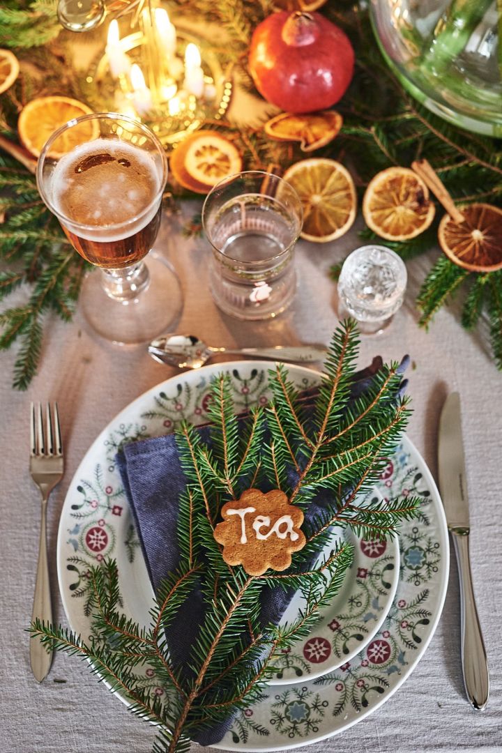 Weihnachtliche Tischdekoration wie im Märchen: Nutzen Sie das Swedish Grace Winter-Porzellan von Rörstrand und platzieren Sie eine Serviette und einen Tannenzweig, sowie einen Keks als Platzzuweiser darauf.
