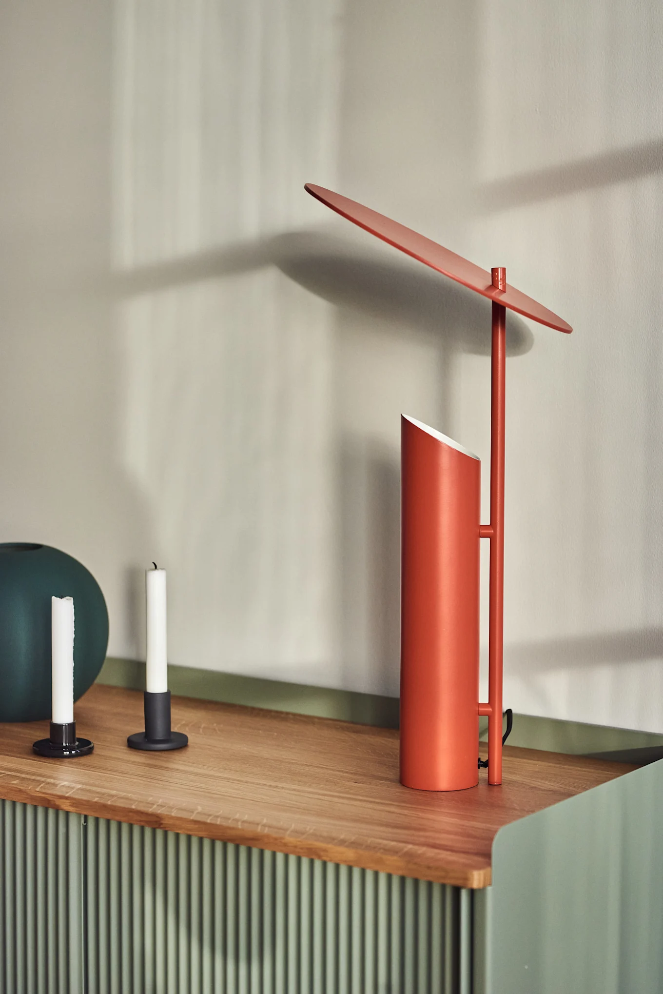 Auf einer Kommode steht die von Verner Panton entworfene Reflect Tischleuchte in Rot von Verpan.