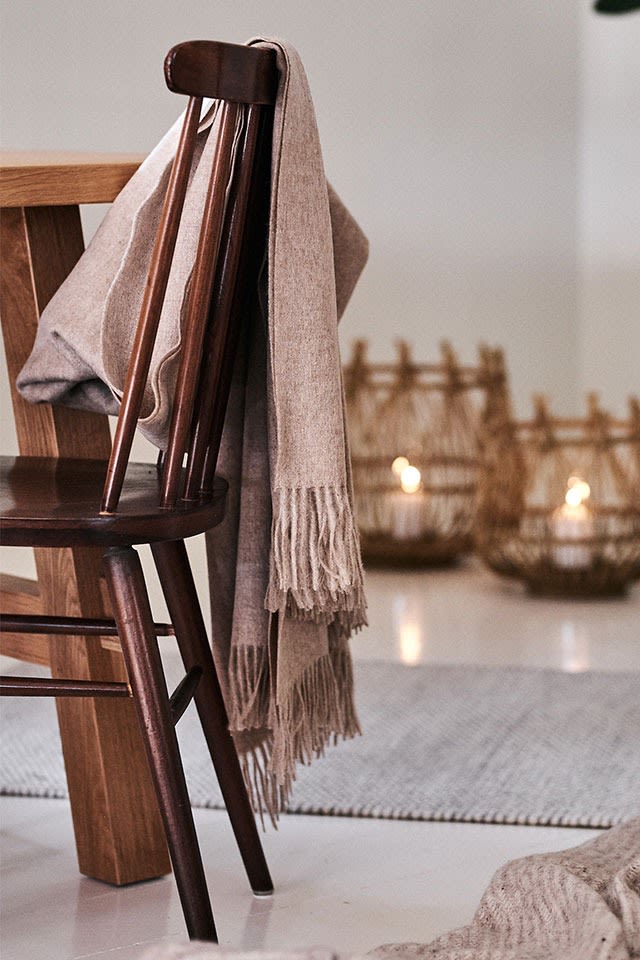 Die beigefarbene Classic Decke von Elvang Denmark hängt über dem Küchenstuhl in einem eleganten Essbereich im Bohème-Stil.