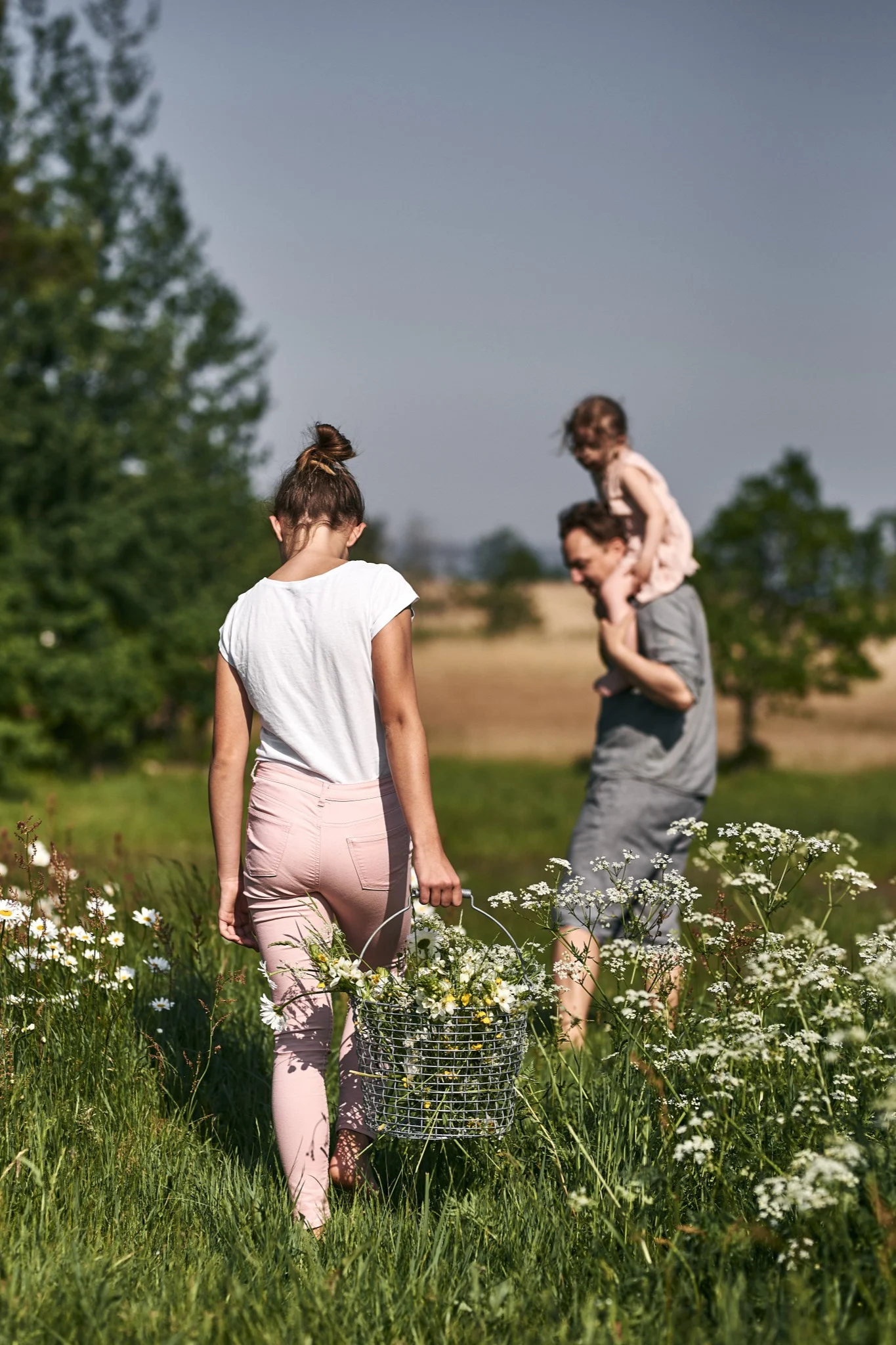 Summer Bucket List: Ein Mädchen pflückt im Sonnenschein Blumen und legt sie in einen Korbo-Korb. Im schwedischen Sommer geht es vor allem darum, Zeit im Freien zu verbringen.