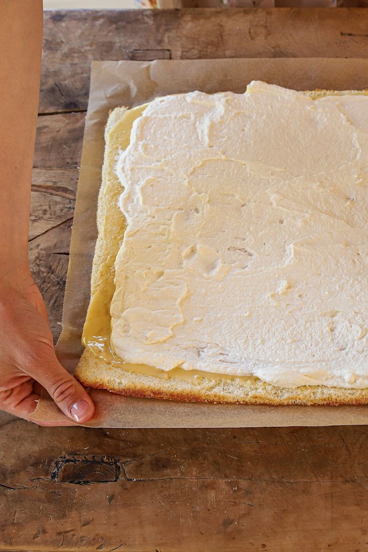Der Biskuitteig wird mit Zitronencreme und Sahne bestrichen.