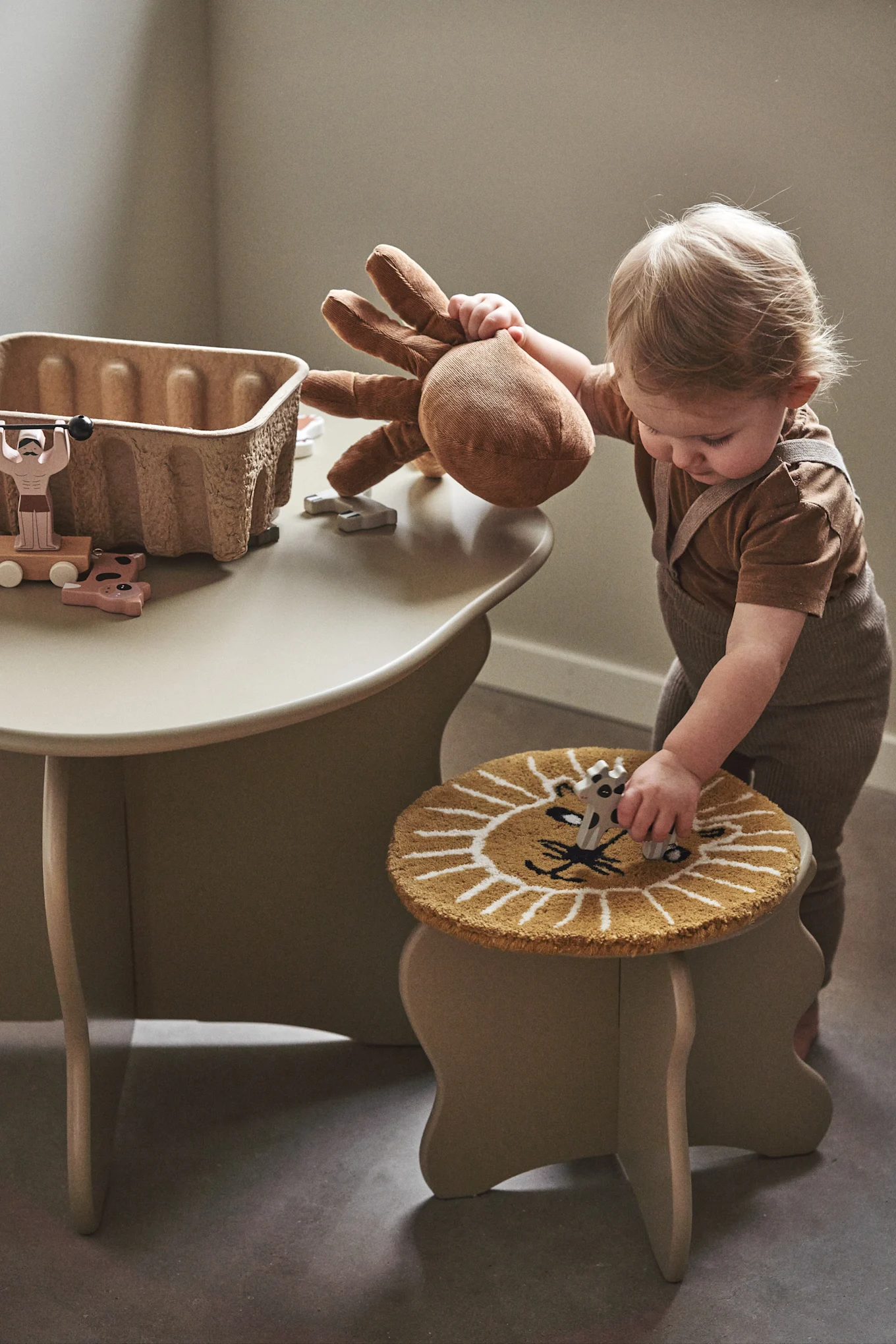 Ein kleiner Tisch und Stühle sind ein Muss in einem Kinderzimmer, hier sehen Sie ein kleines Kind mit dem Slope Tisch und Hocker von Ferm Living. 