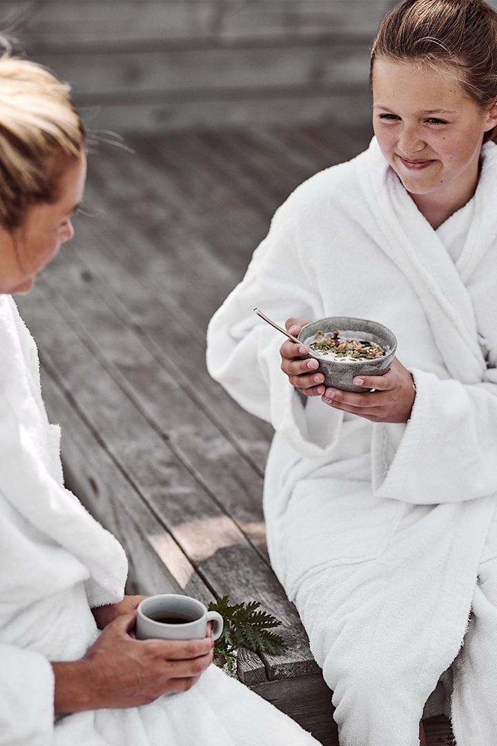 Gemütliches Frühstück auf dem Steg am Wasser mit Smoothie Bowl und Kaffee in der Hand. 