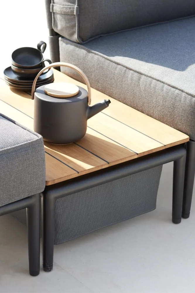 Der Conic Couchtisch von Cane-line dient nicht nur als Ablagefläche, sondern bietet auch Stauraum für Decken oder Kissen und zählt somit zu Recht zu den Gartenmöbel-Trends 2025.