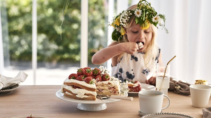 Eine Erdbeertorte auf einer weißen Tortenplatte mit einem ERNST-Tortenheber. 