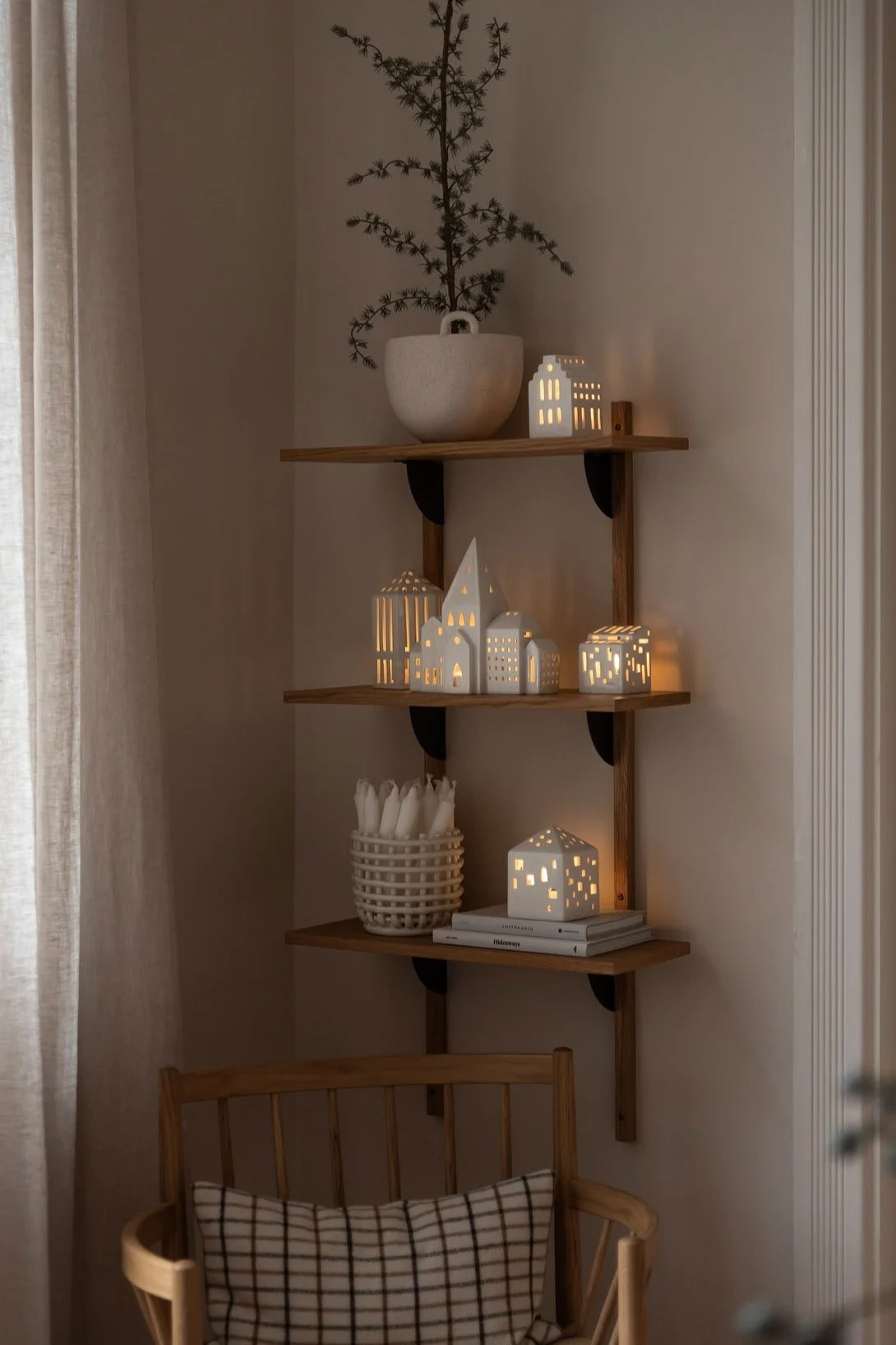 Moderne Weihnachtsdeko in einem neutralen Beige- und Weißton im Wohnzimmer. Hier sehen Sie die Kerzenhalter „Urbania“ von Kähler auf einem Regal.