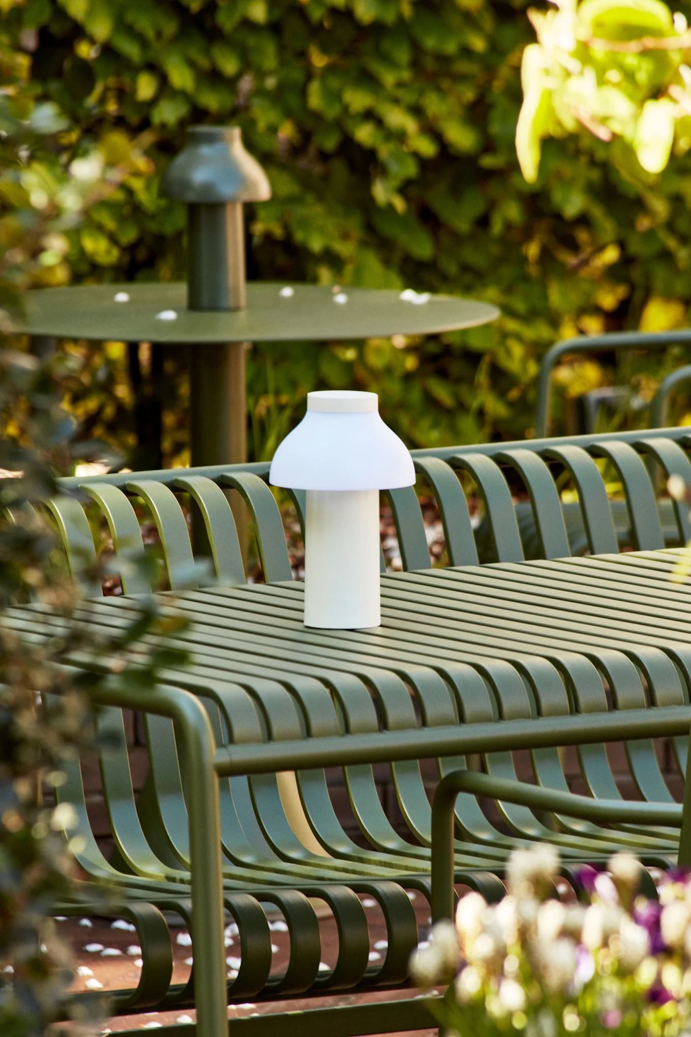 Die PC Portable White Akku-Tischleuchte ist eine wiederaufladbare Lampe, die im Freien auf einem grünen Tisch steht. 