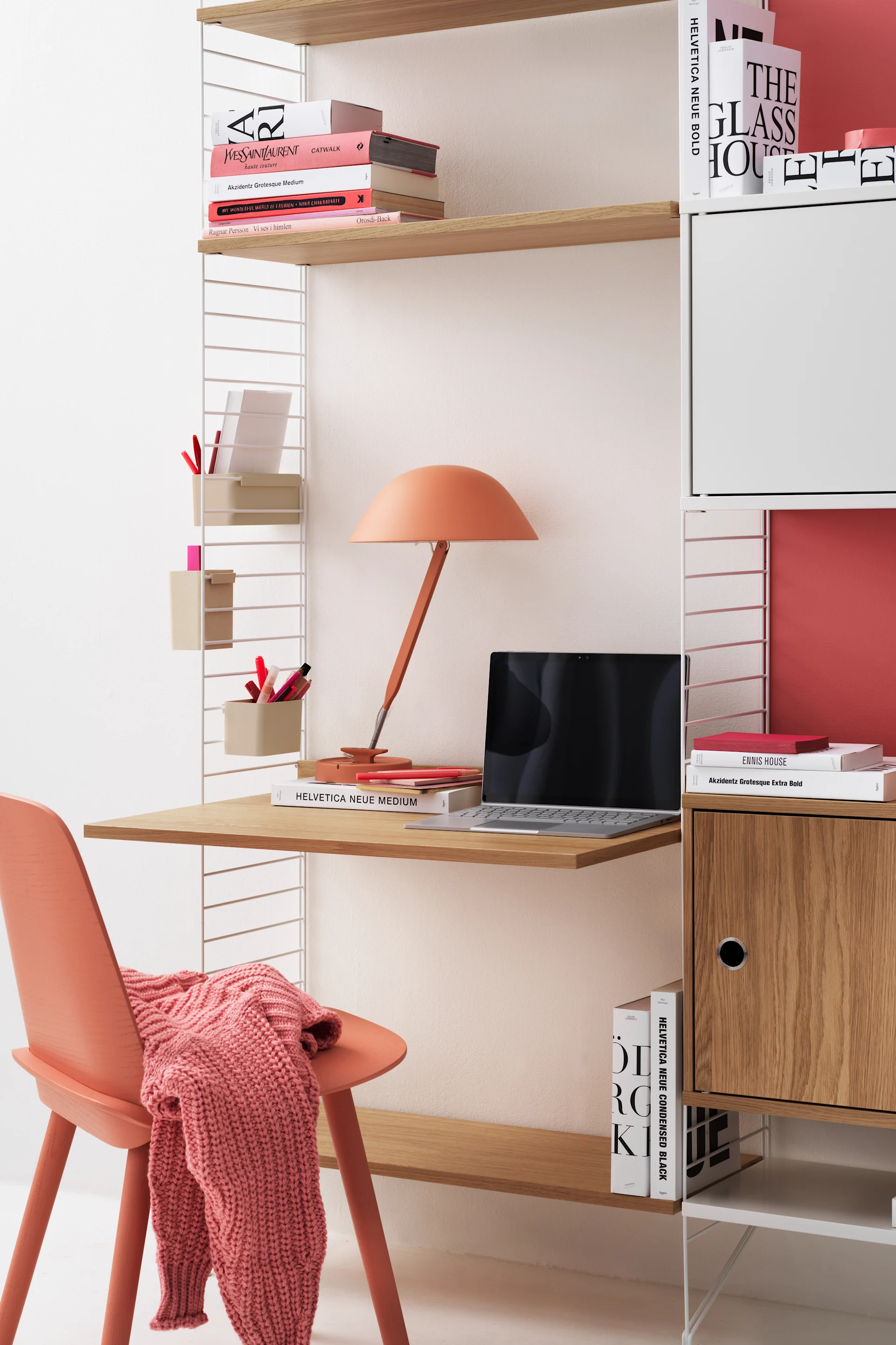 String Regalsystem: Hier sehen Sie ein String-Regal, welches als Schreibtisch verwendet wird und mit roten und orangefarbenen Elementen dekoriert worden ist.