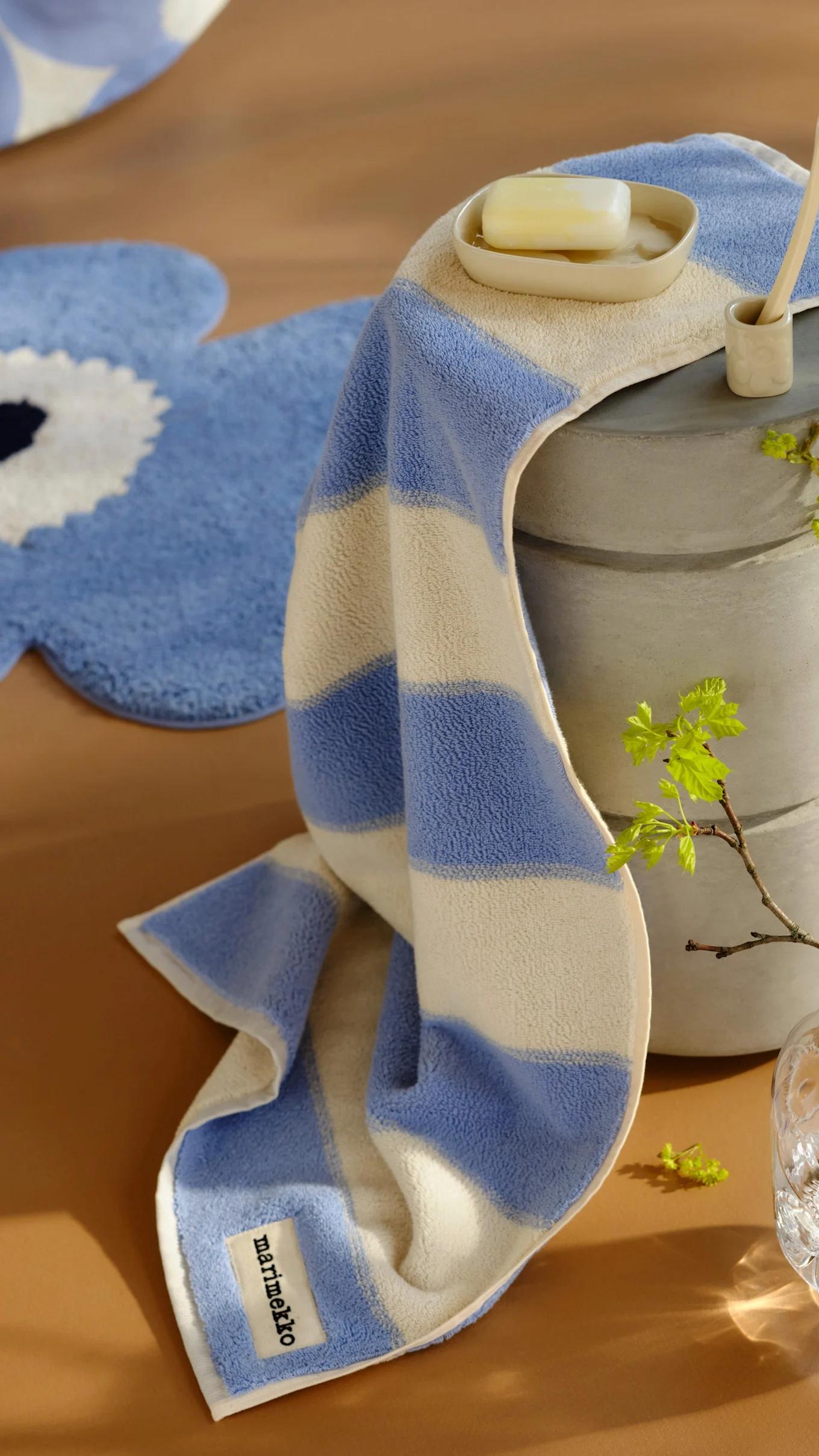 Stapel von vier Kissen mit abstrakten und floralen Mustern in Beige, Rosa und Schwarz auf einem Holzhocker. Ein weiteres gemustertes Kissen liegt auf dem Boden.