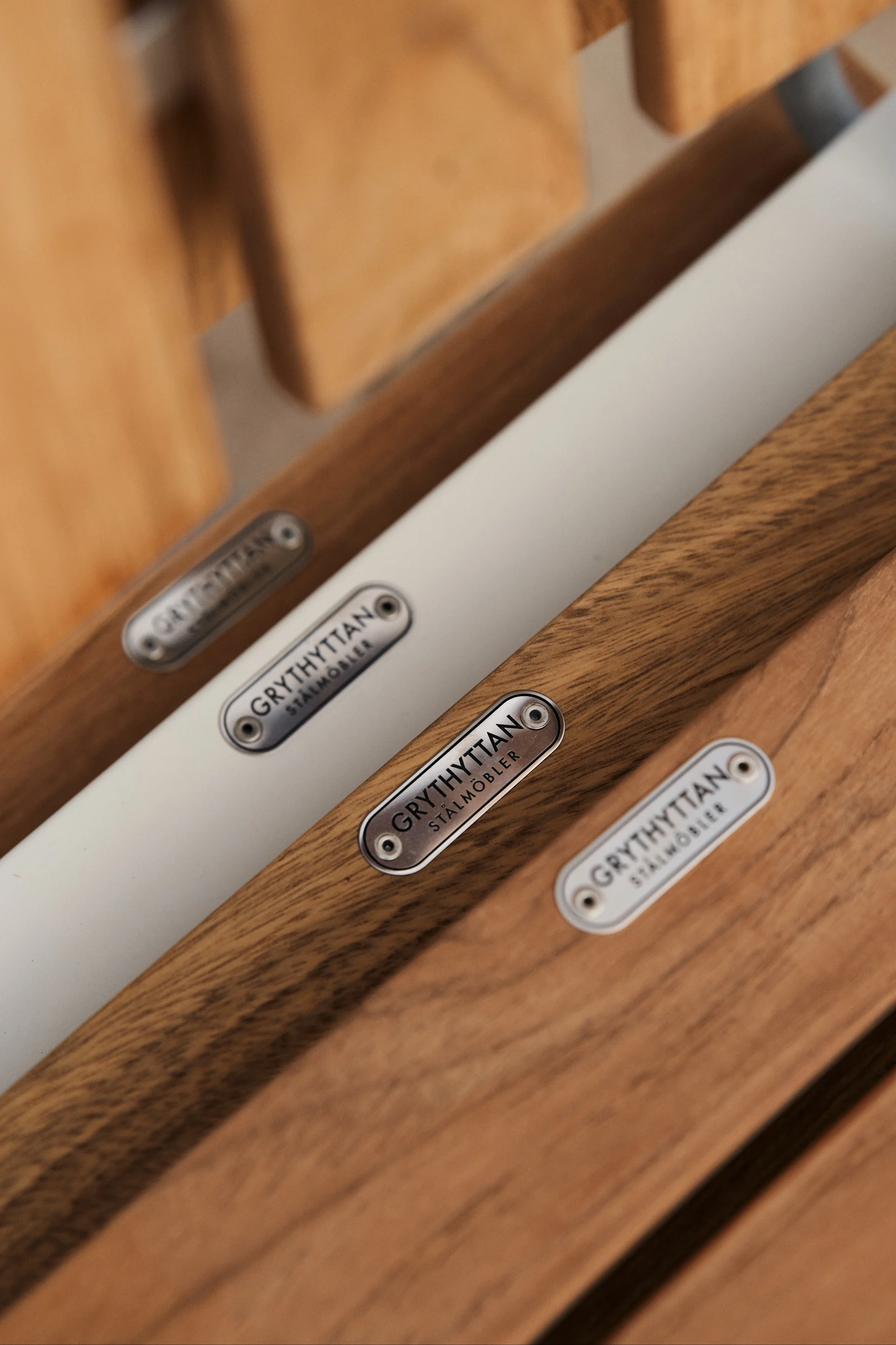 Gartenmöbel aus Teak pflegen: Der A2-Stuhl von Grythyttan Stålmöbler ist eine Ikone unter den Outdoor-Möbeln aus Teakholz, hier ein Detailbild der Sitzfläche, auf der das Logo aus verzinktem Stahl wie ein schönes Detail sitzt.