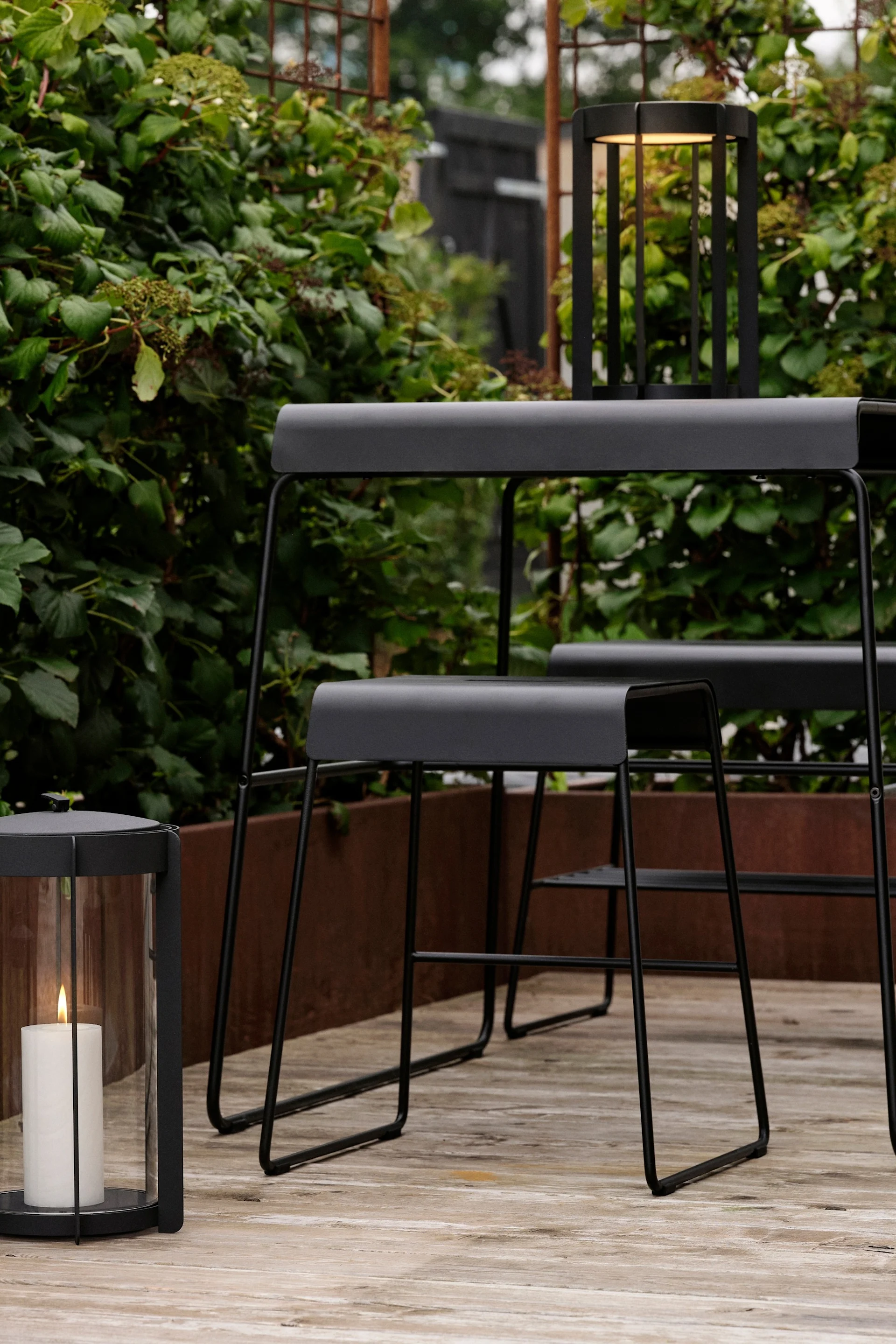 Tisch und Hocker aus der Outdoor-Kollektion von Zone Denmark stehen draußen auf einer Terrasse.