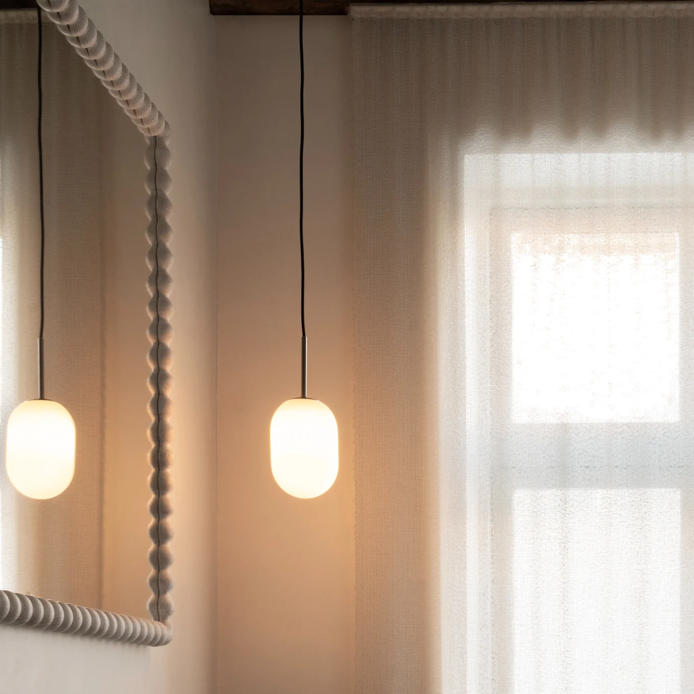 Modernes Badezimmer: Holzwaschtisch, dunkles Waschbecken, Bronzehahn, strukturiertes Spiegel, Pendelleuchten, transparente Vorhänge.