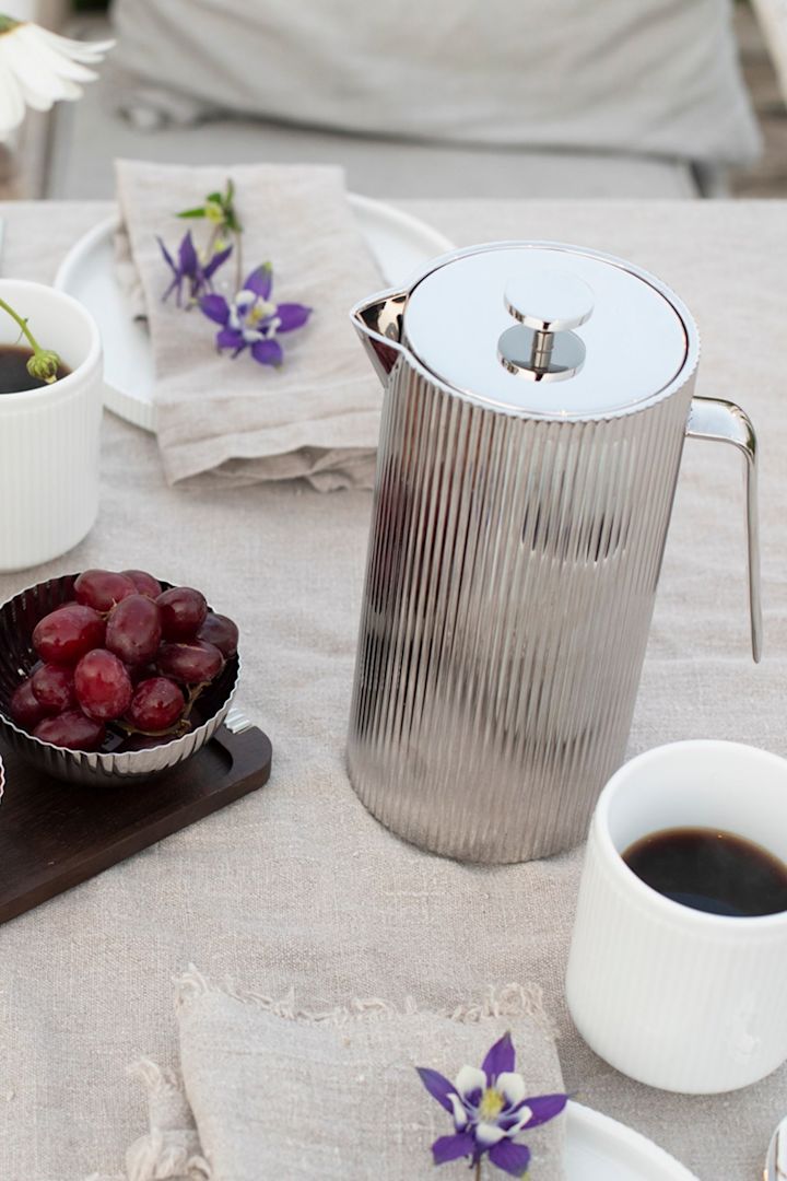 Die Bernadotte Stempelkanne von Georg Jensen, hier auf einer Picknickdecke, ist eine stilvolle Hochzeitsgeschenk-Idee.