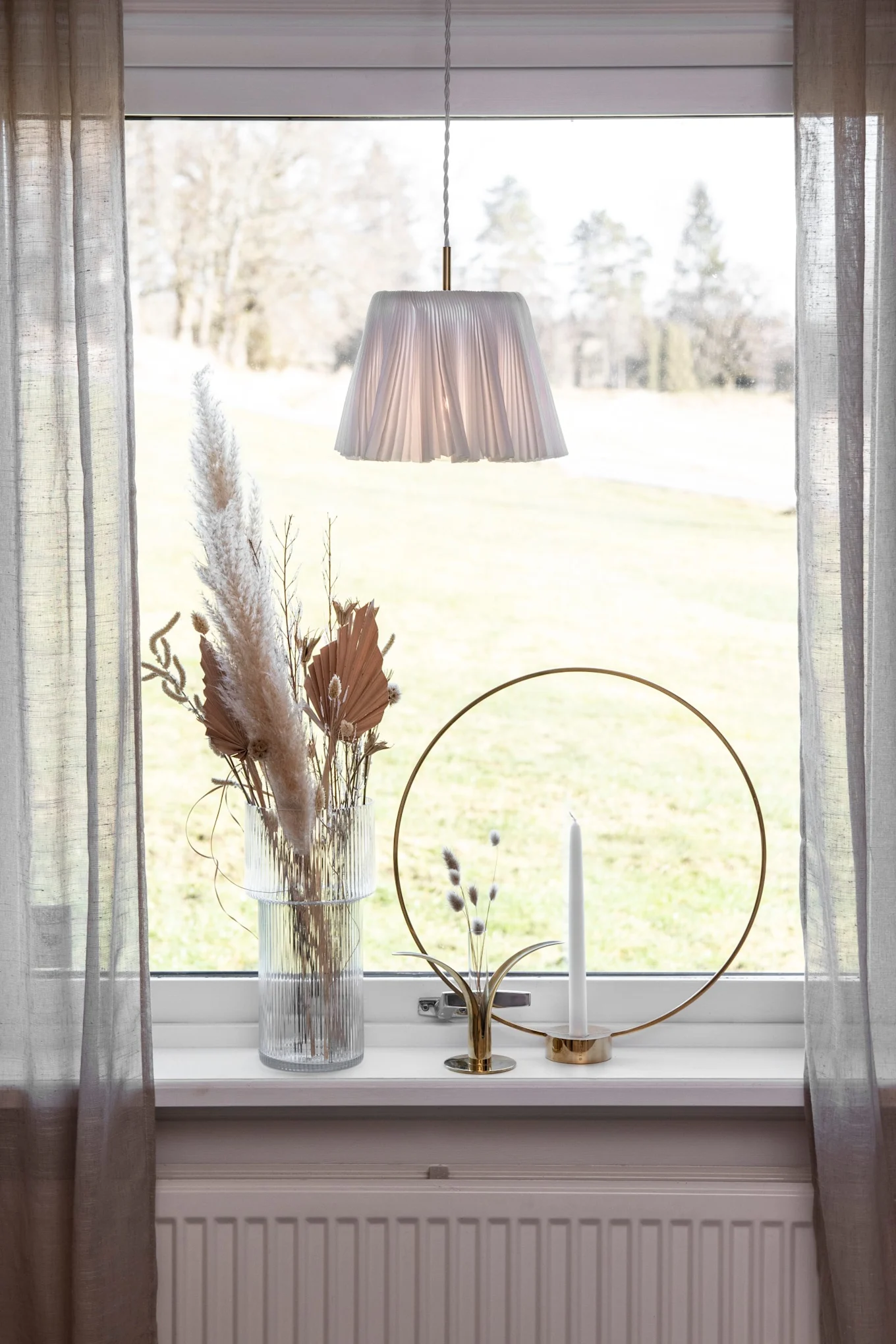 Fensterbank dekorieren: Ein Fenster mit Gardinen, einer Vase mit Trockenblumen und dem Klong Kerzenhalter Gloria.