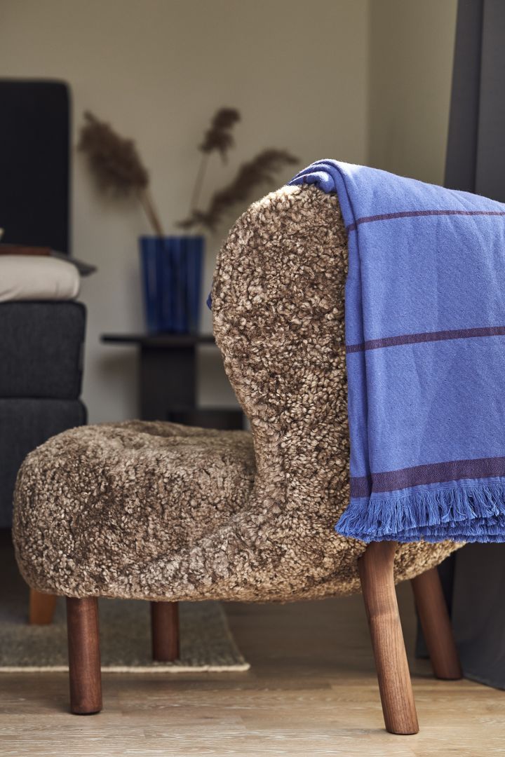 Wolle, Holz und blaue Akzente – der Little Petra Sessel und ein blaues Plaid von &tradition sind genau das Richtige für die Wohntrends 2023. 