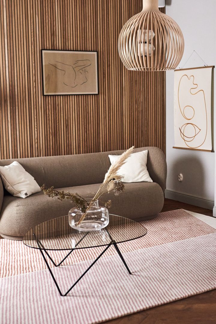 Dekorieren Sie Ihr Wohnzimmer mit beigen Möbeln in Kombination mit Farbe für einen lebendigen Look in Ihrem Zuhause. Hier sehen Sie den Wollteppich Rectangles von NJRD in Rosatönen zusammen mit dem Couchtisch Gubi Pedrera, der Urna Vase von Marimekko und dem Poster Sunkissed von Paper Collective.